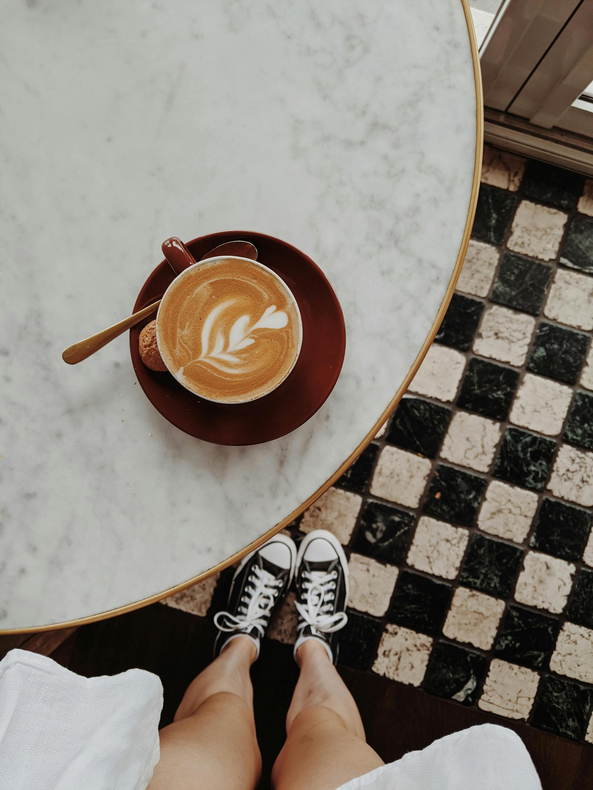 Vista superior de una mesa de mármol con una taza de café con arte latte
