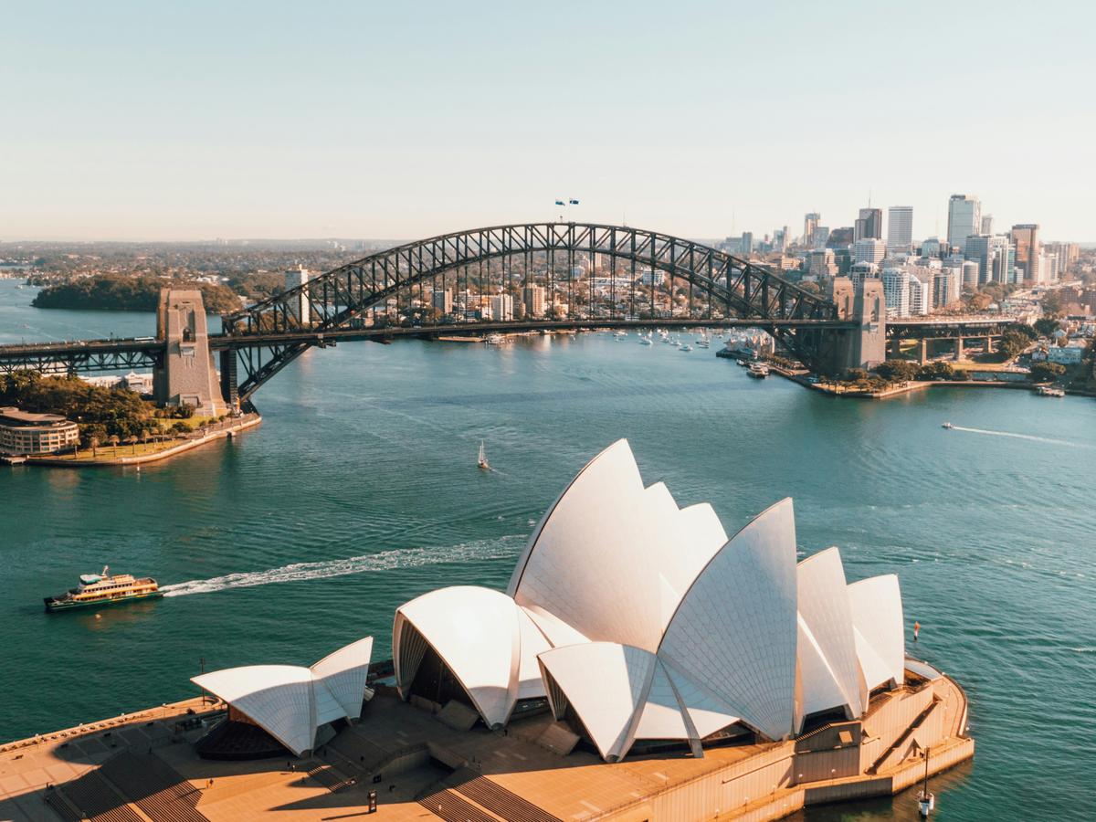 Vista panorámica aérea de la Ópera de Sydney y el puente de la bahía en Australia bajo un cielo despejado.