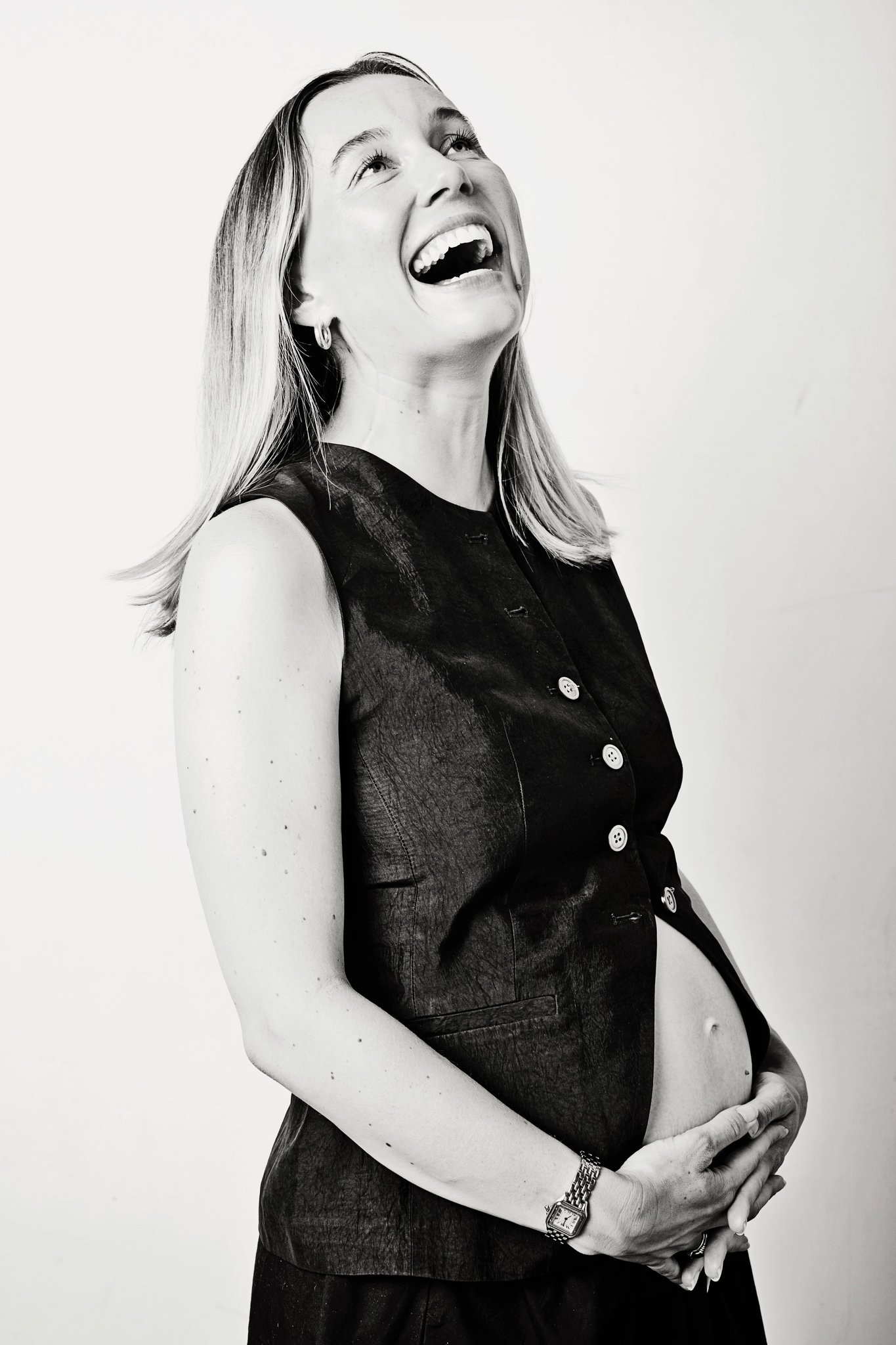 An expecting mother laughing, in black and white
