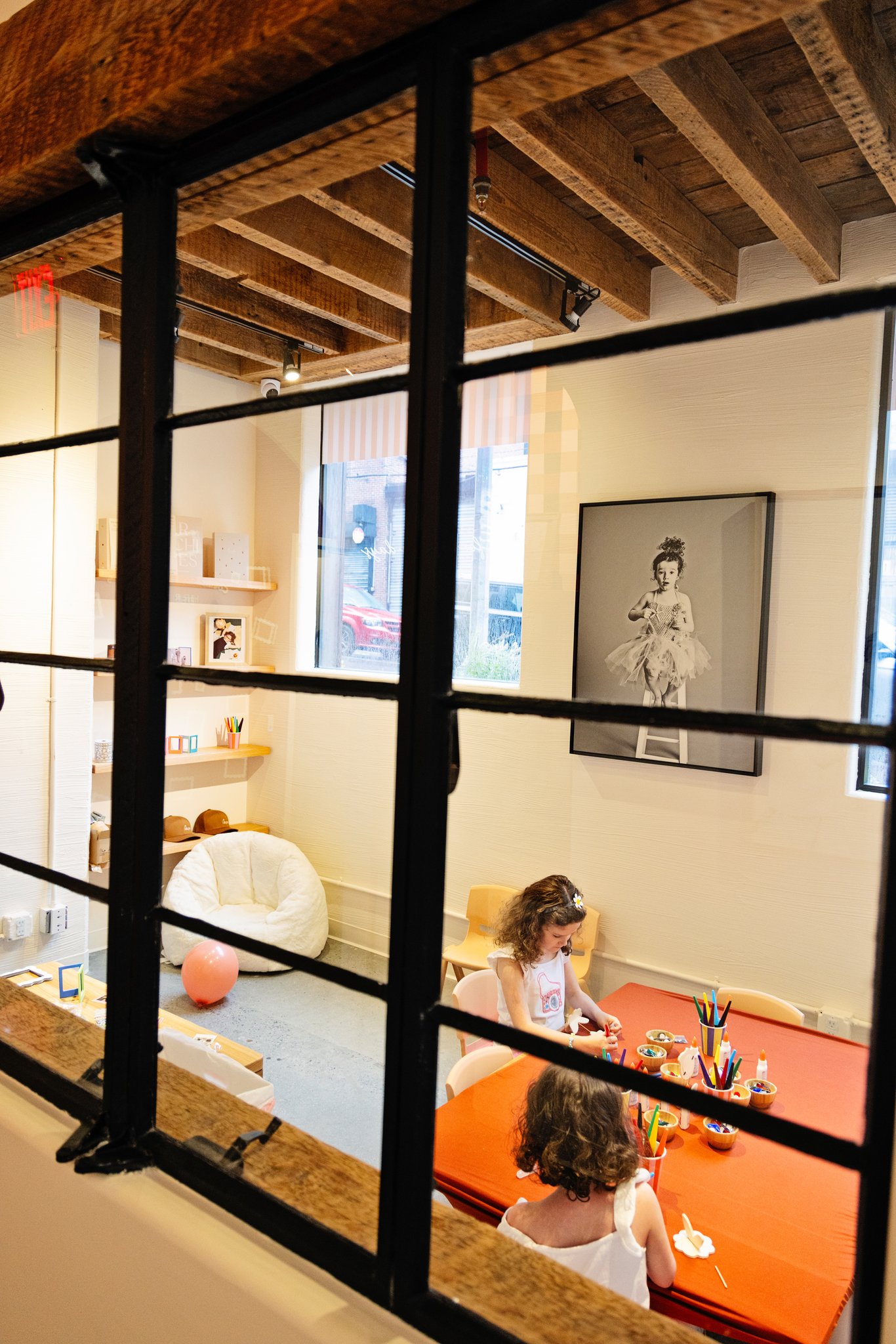 Kids at the craft table behind the glass playroom doors