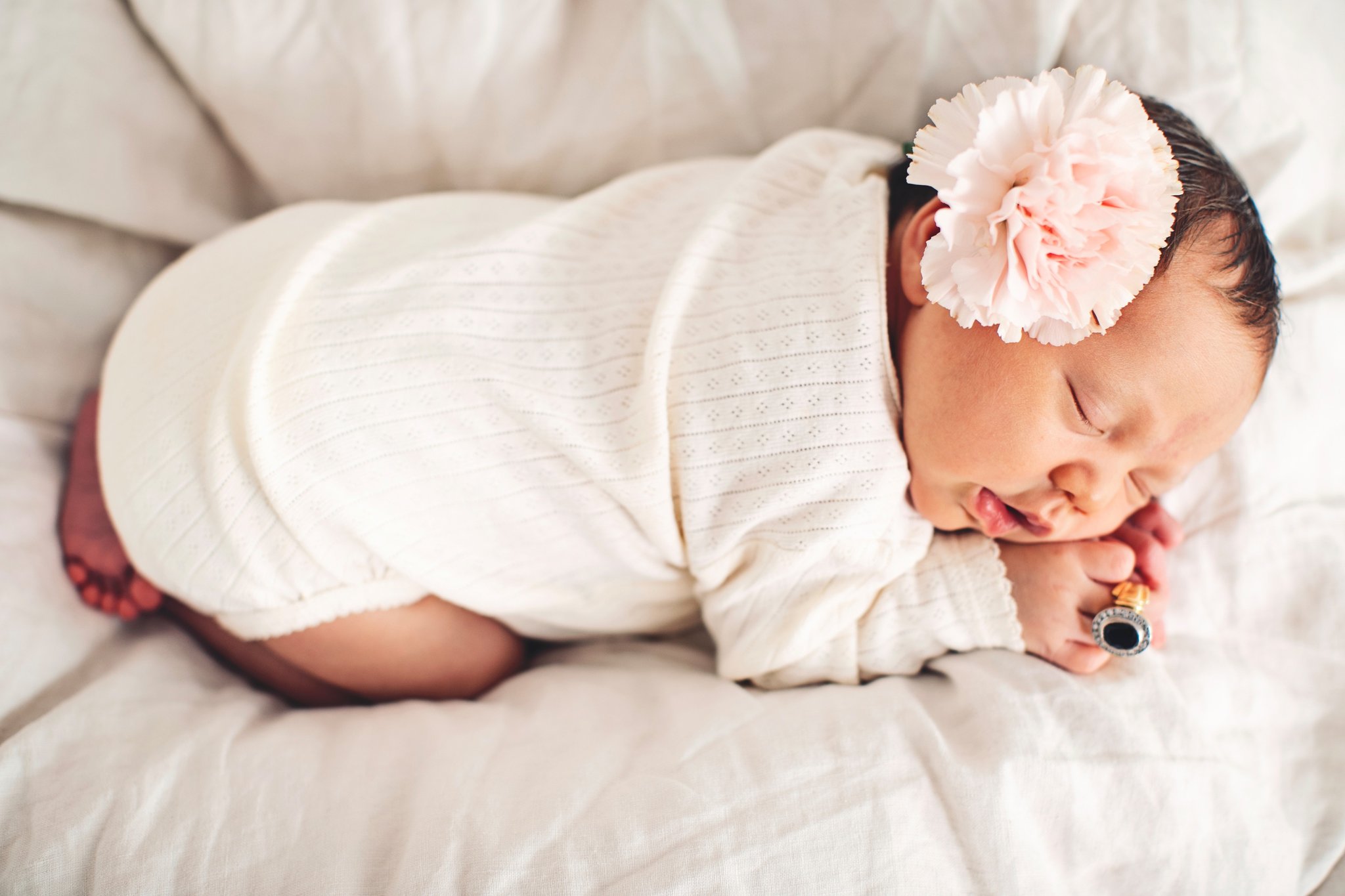 A swaddled newborn in a pink flower headband