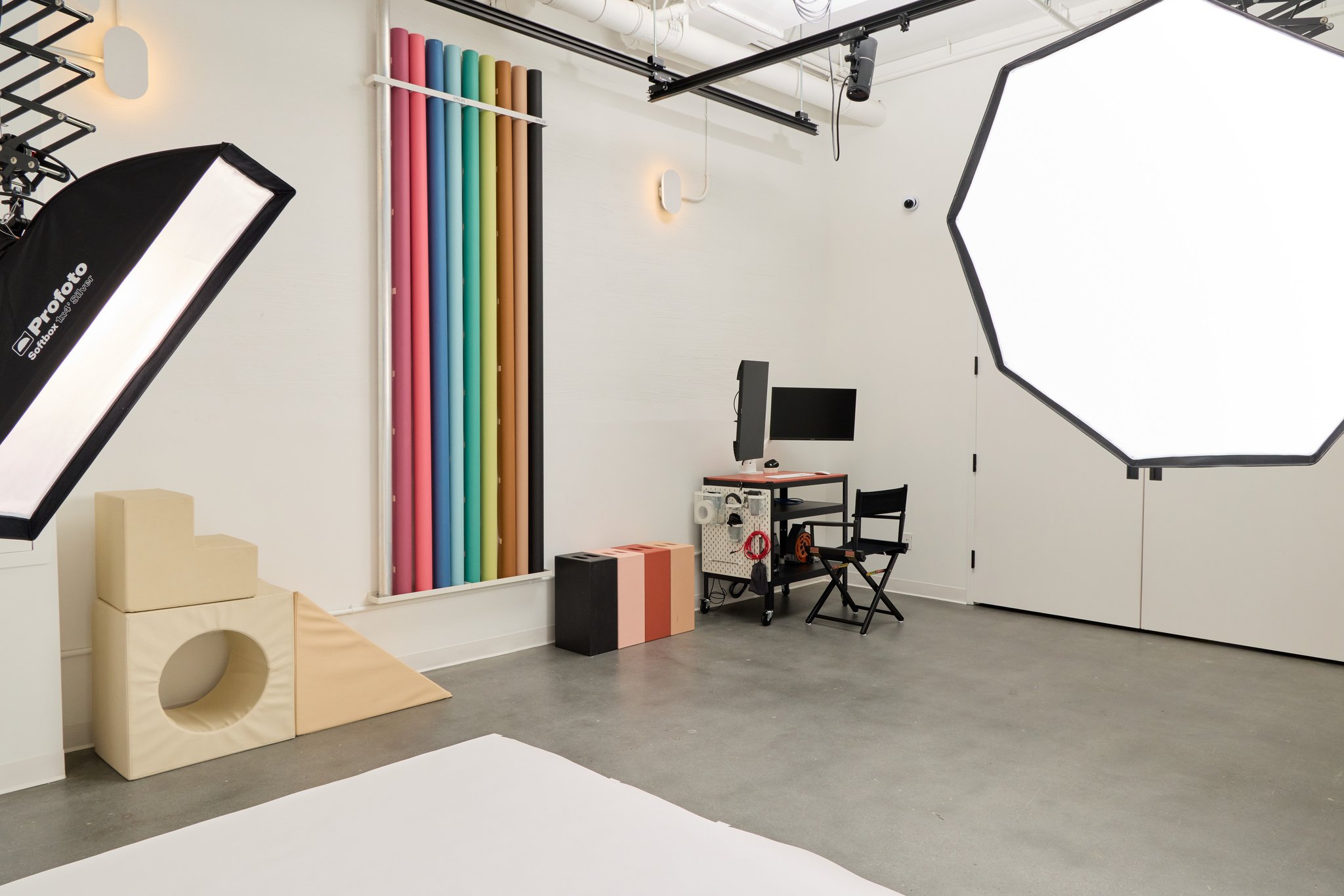 The studio from the side: a large octagonal softbox, stacked posing blocks, the backdrop wall and the tethering station