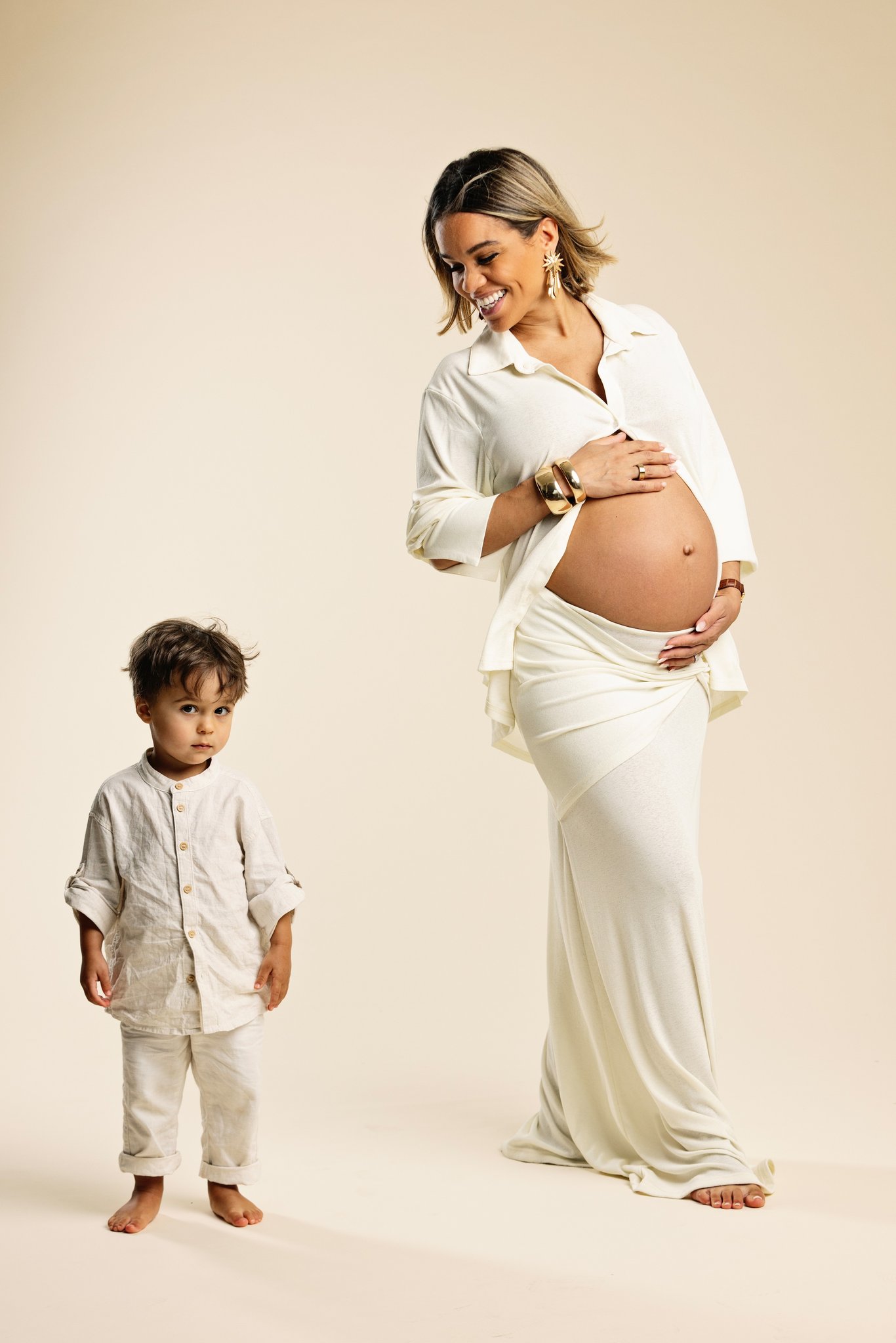 An expectant mother with her son on a white backdrop