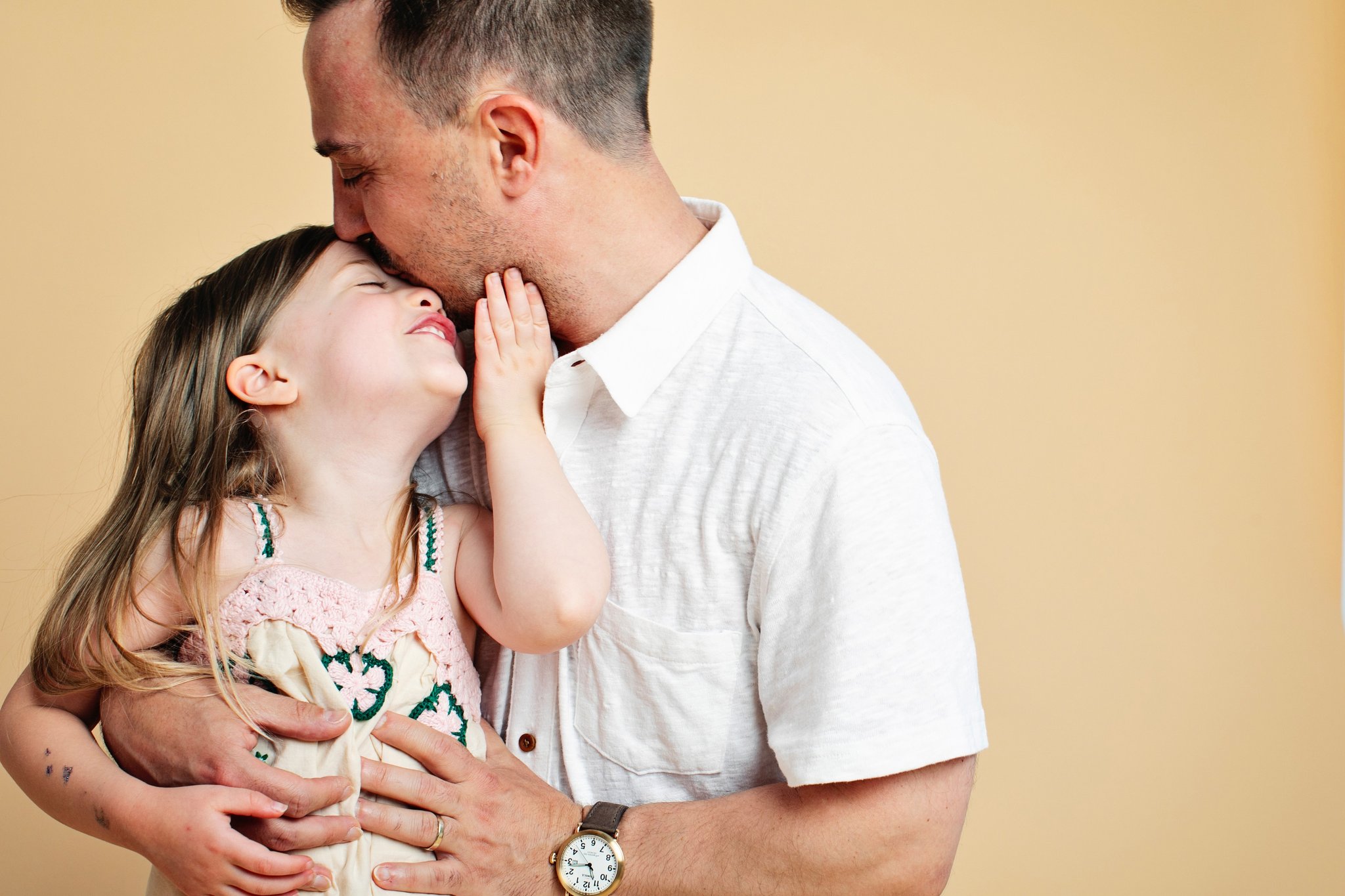 A father kissing his daughter’s forehead