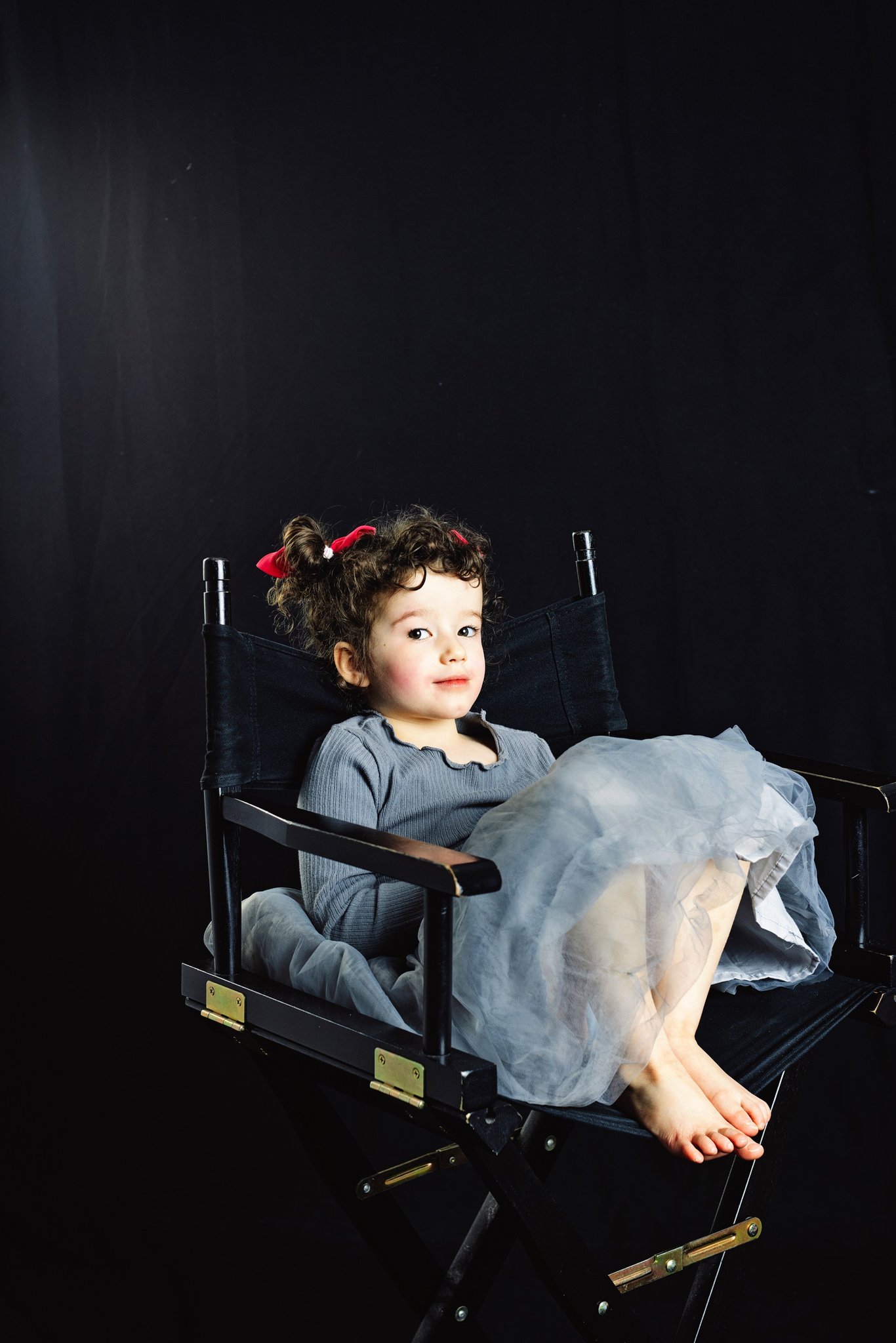 A girl in a tulle skirt curled up in a director’s chair