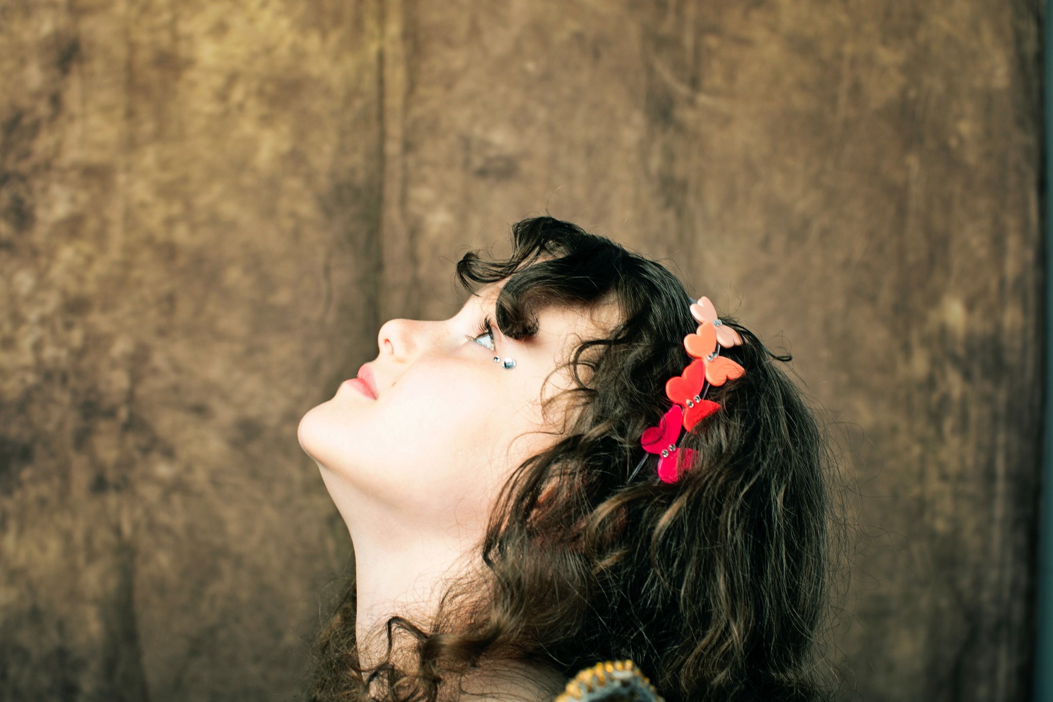 A girl in a heart headband looking up, on a canvas backdrop
