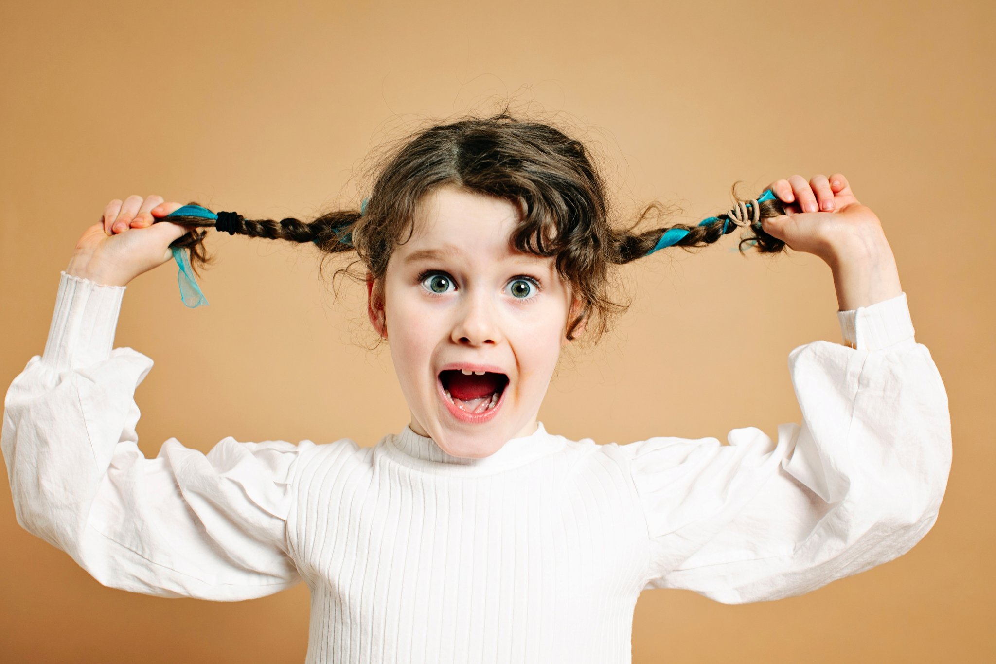 A girl pulling her braids out wide, mouth open