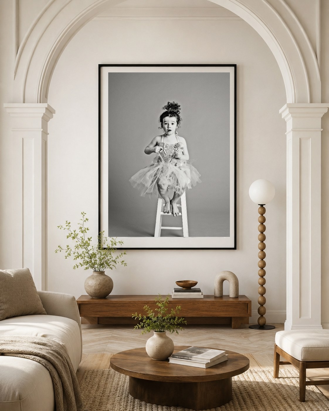 A large framed black and white portrait of a girl in a tutu above a console table
