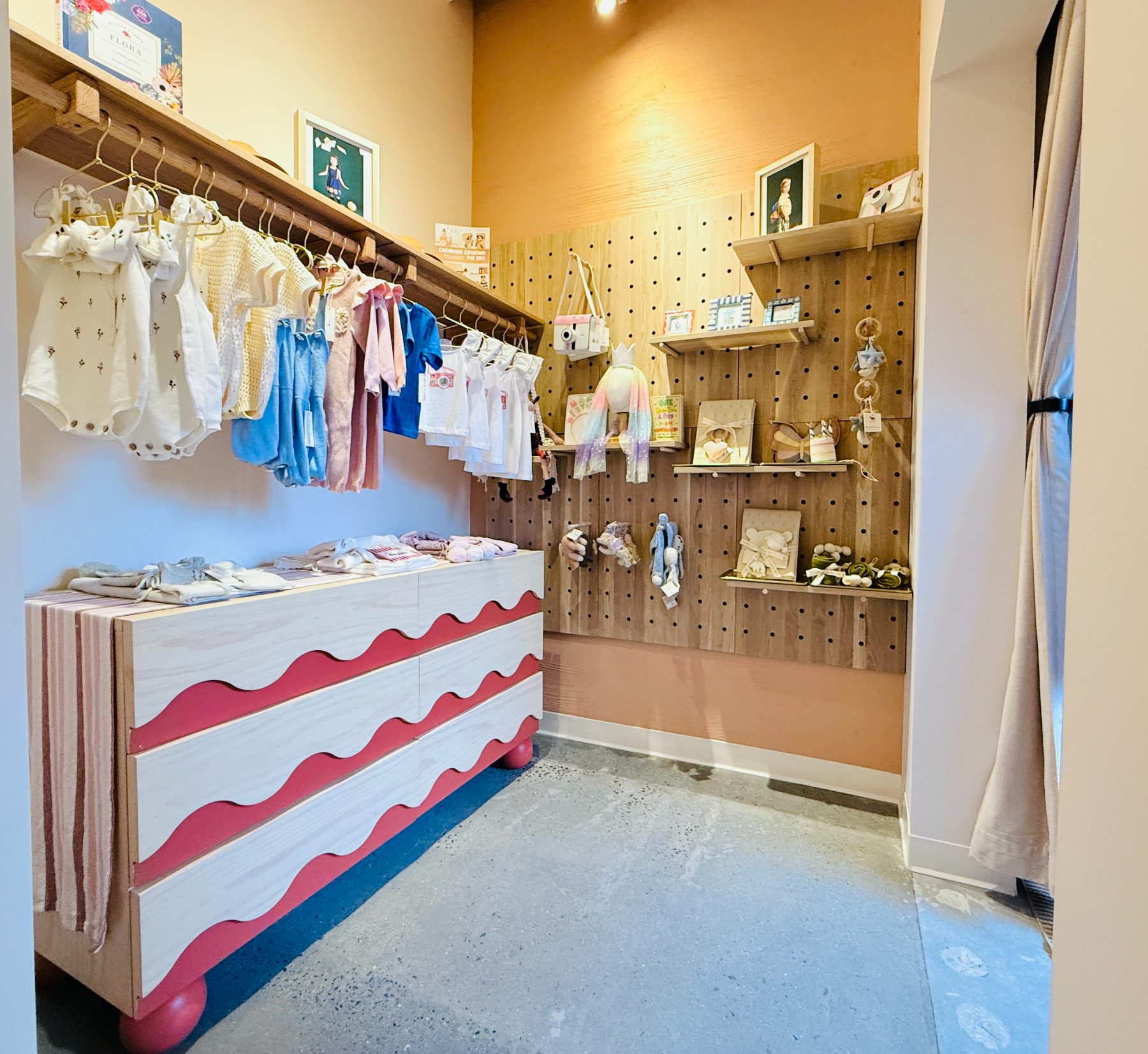 The retail room with children’s clothing rails and a pegboard wall