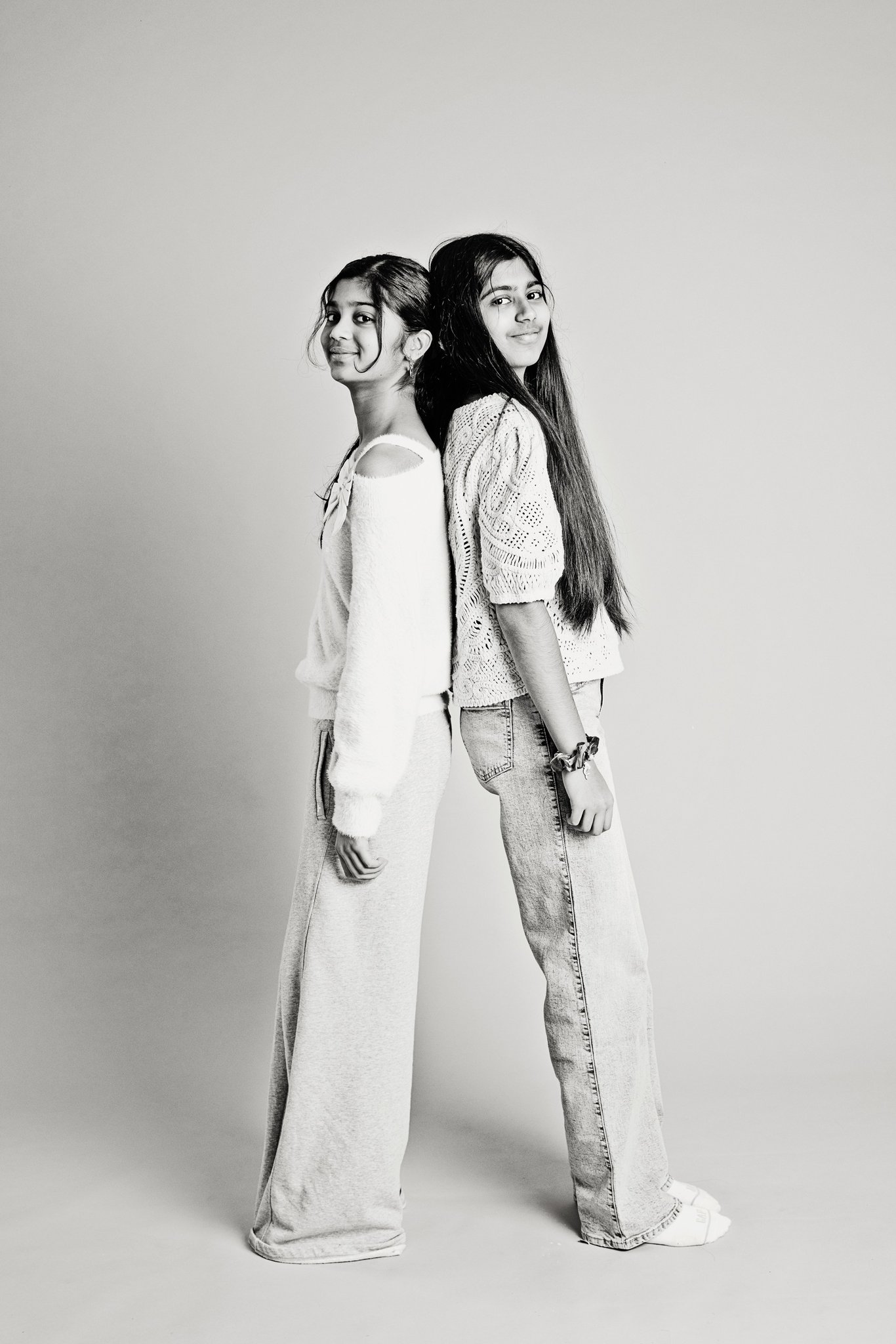 Two sisters standing back to back, in black and white