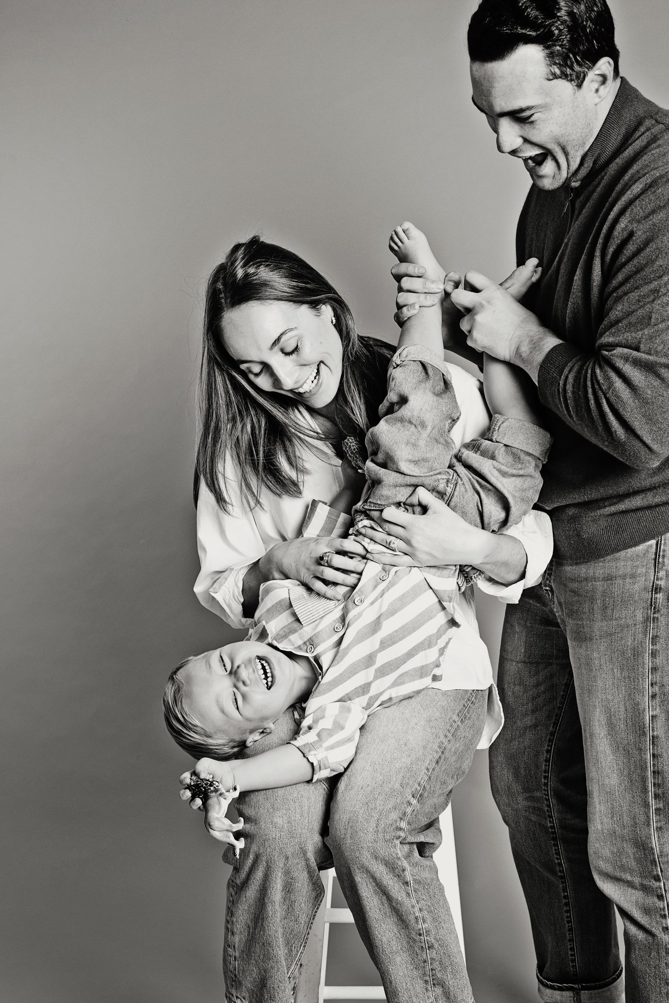 A boy held upside down by his family
