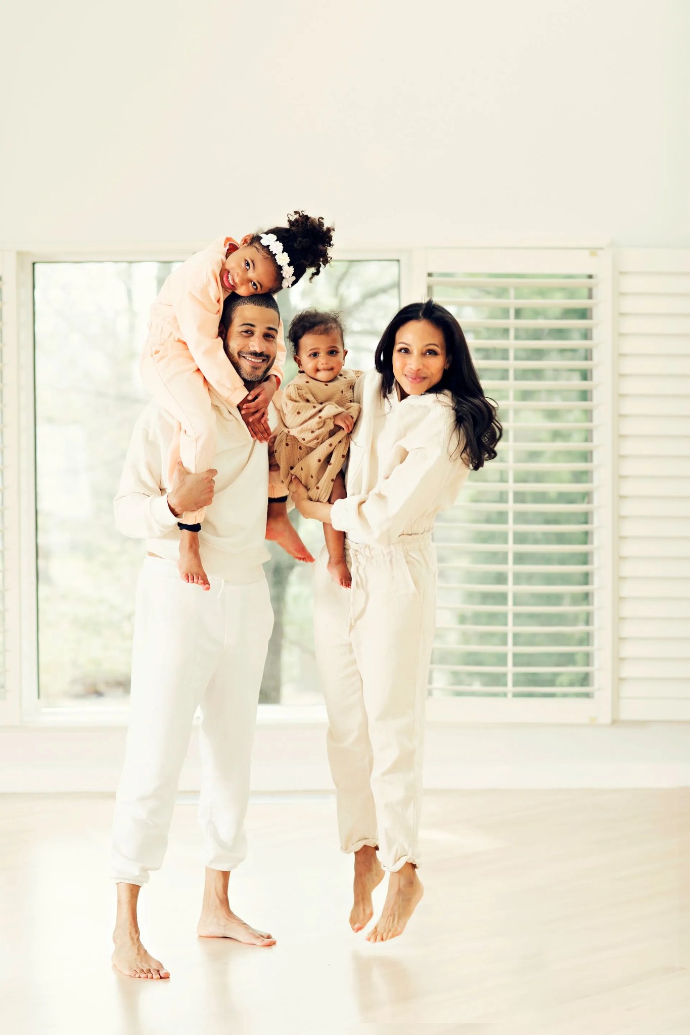A family of four standing together in a bright room at home