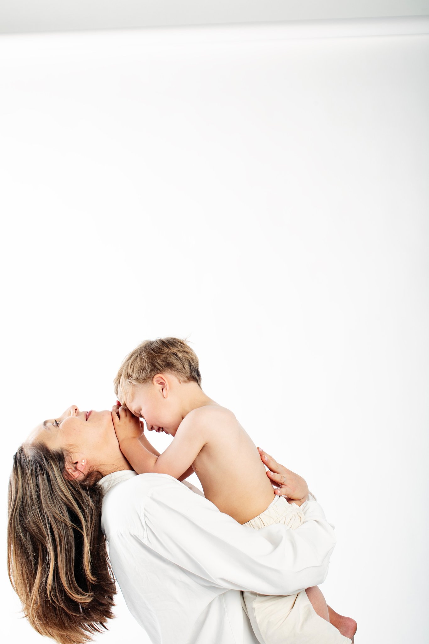 An expecting mother holding her son nose to nose