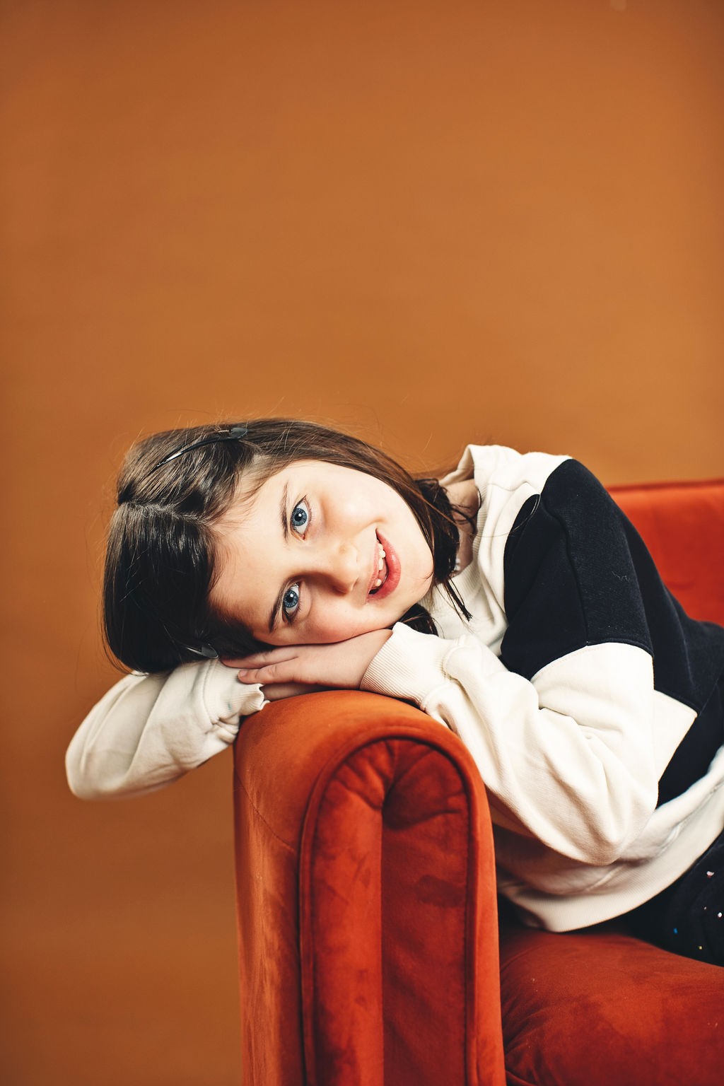 A girl resting her head on the arm of a velvet chair