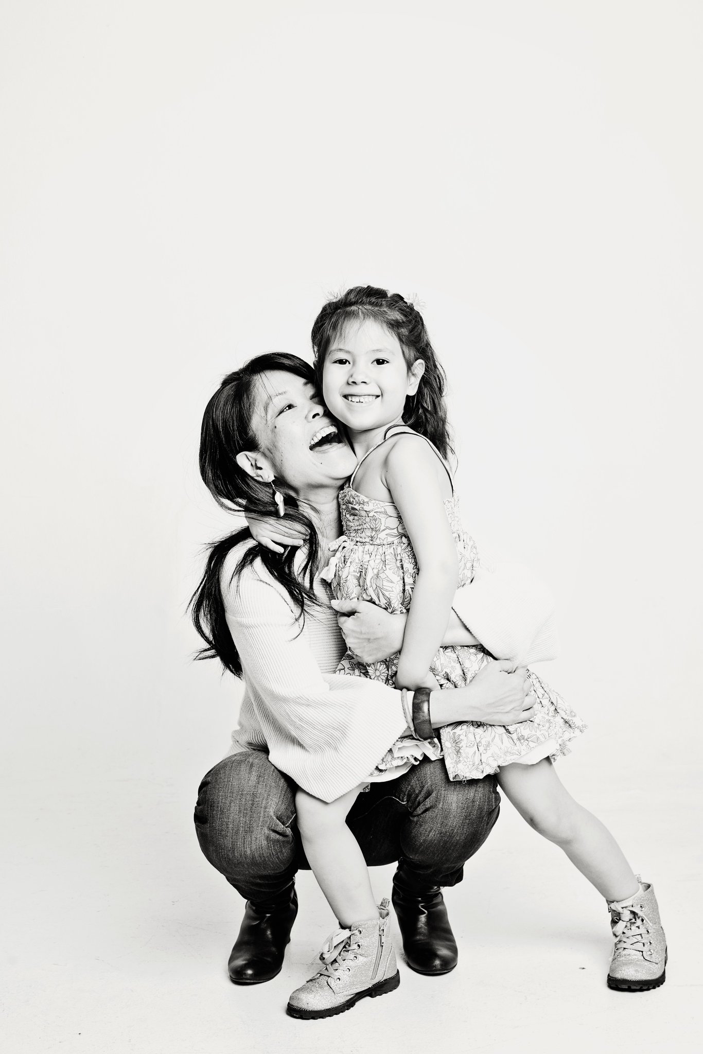 A mother squeezing her daughter, in black and white