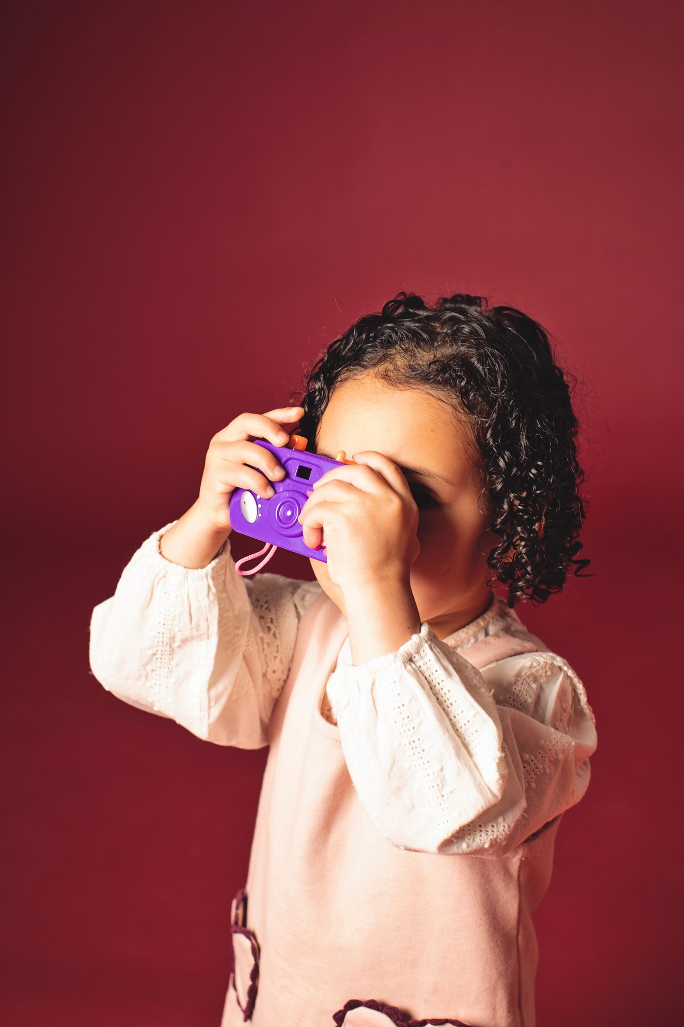 A girl holding a purple toy camera