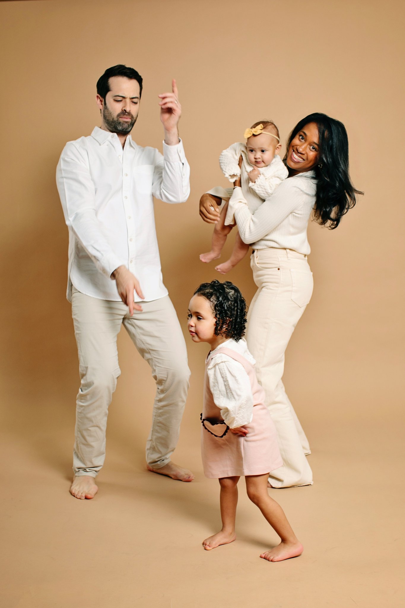 A family of four dancing on a tan backdrop