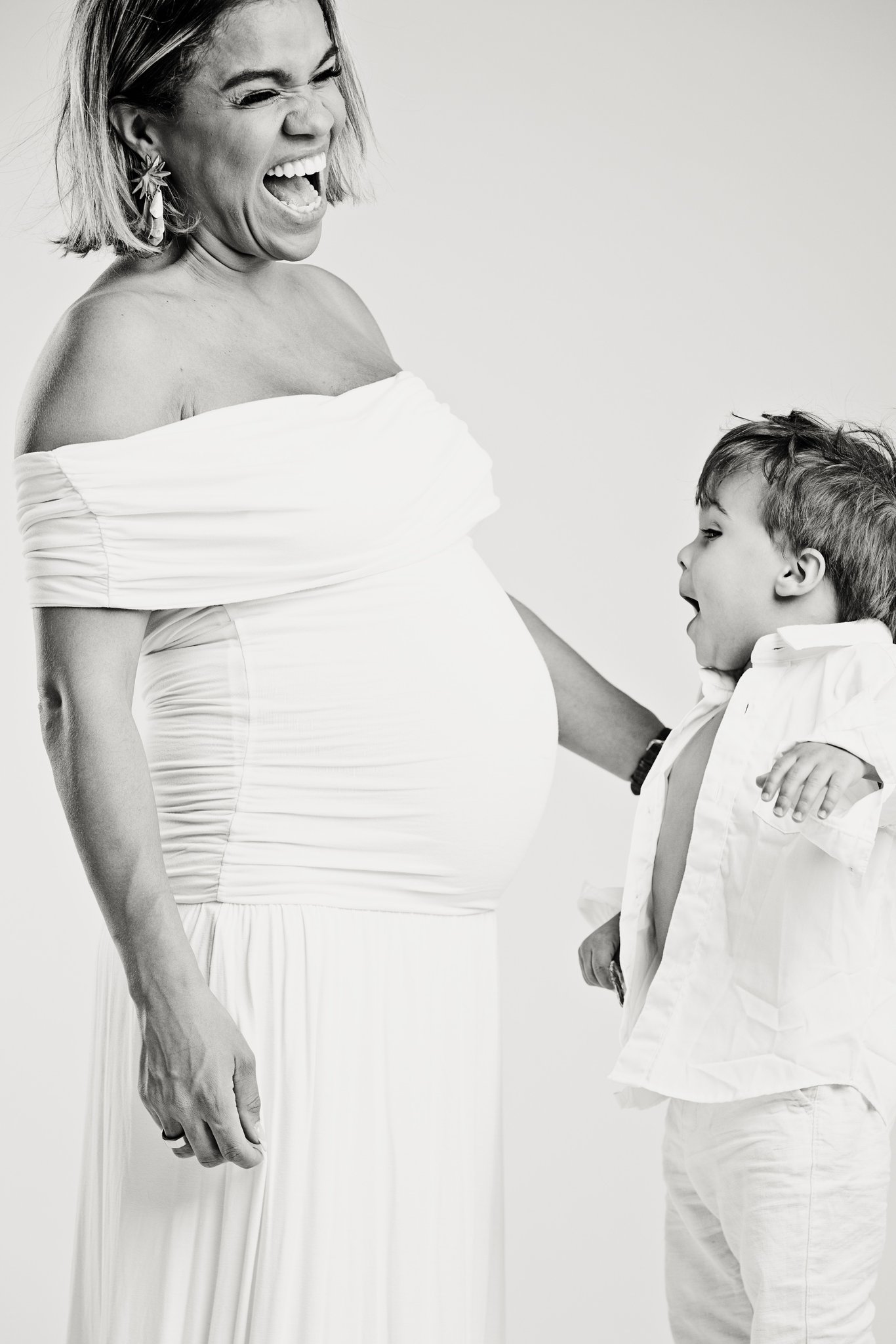 An expecting mother and her son laughing, in black and white