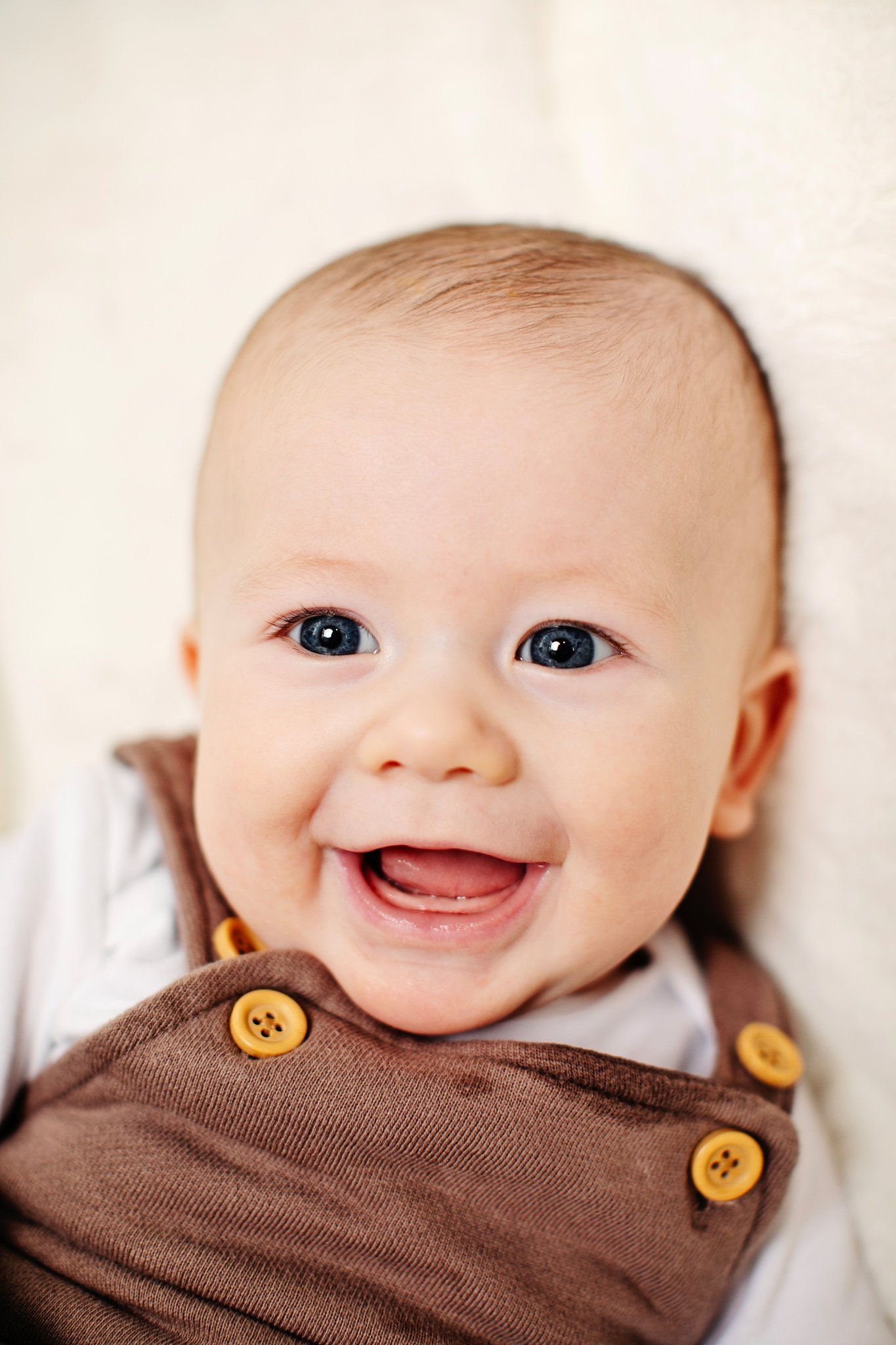 A smiling baby in brown button overalls