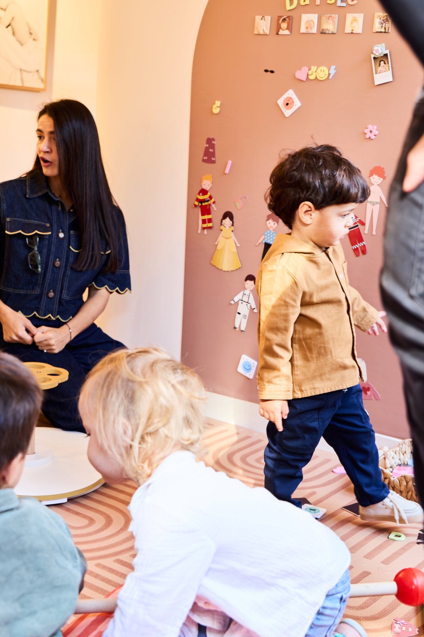 A little boy dancing on the rug while a mother looks on