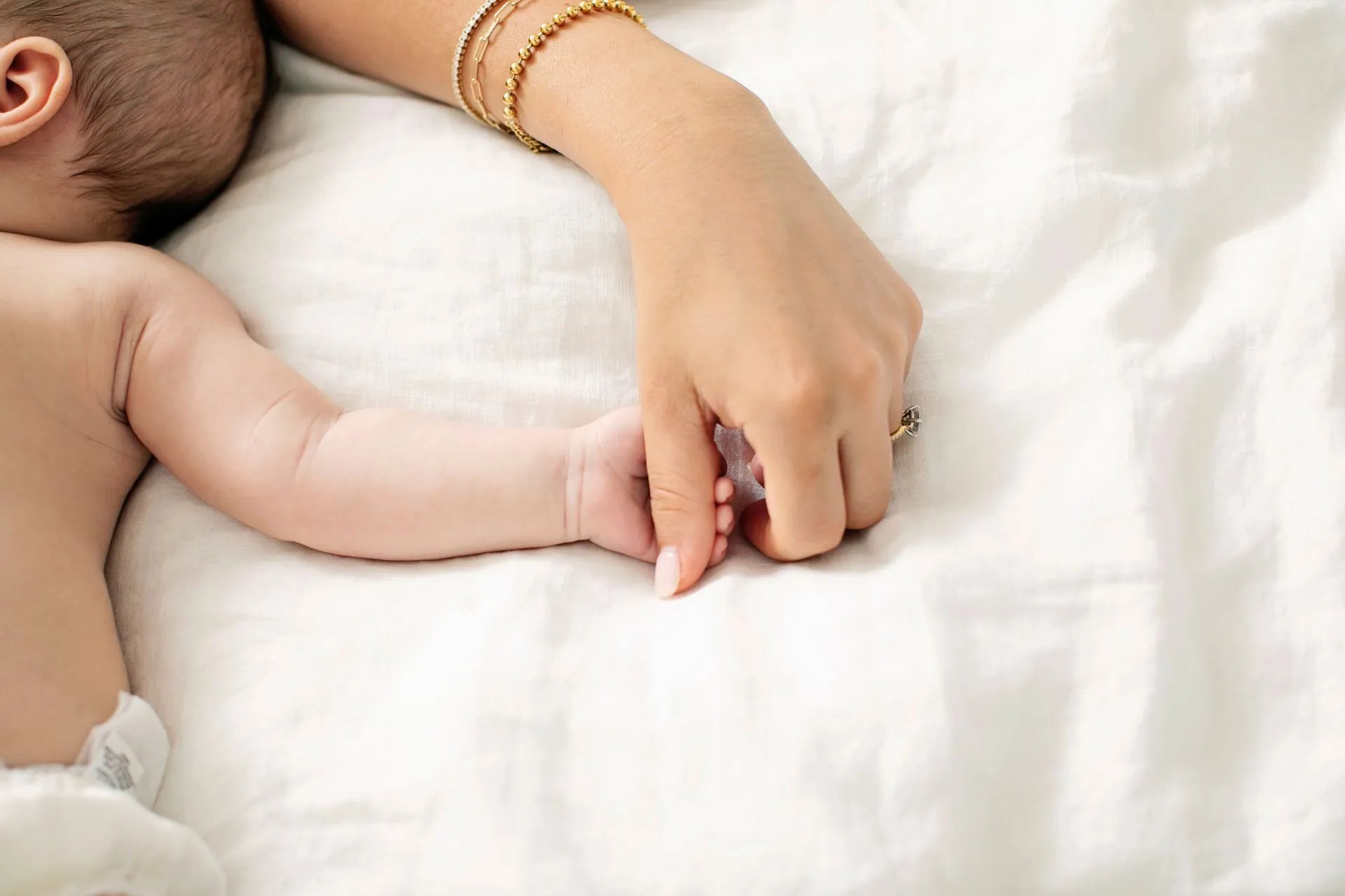 A baby’s hand resting on their mother’s hand