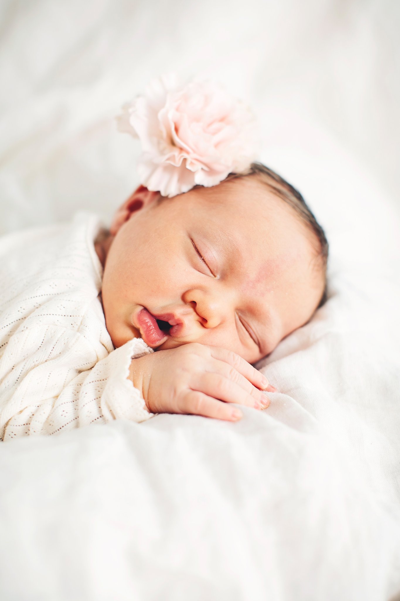 A sleeping newborn in a pink flower headband
