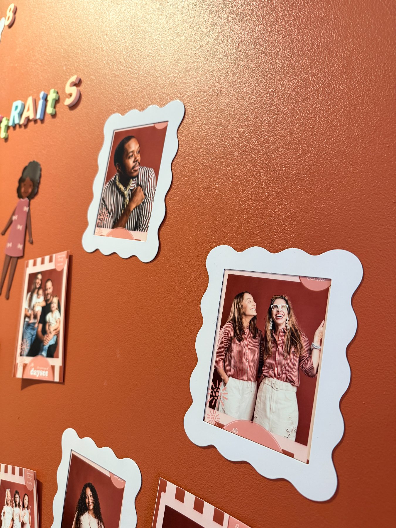Wavy white frames holding portraits on a terracotta wall