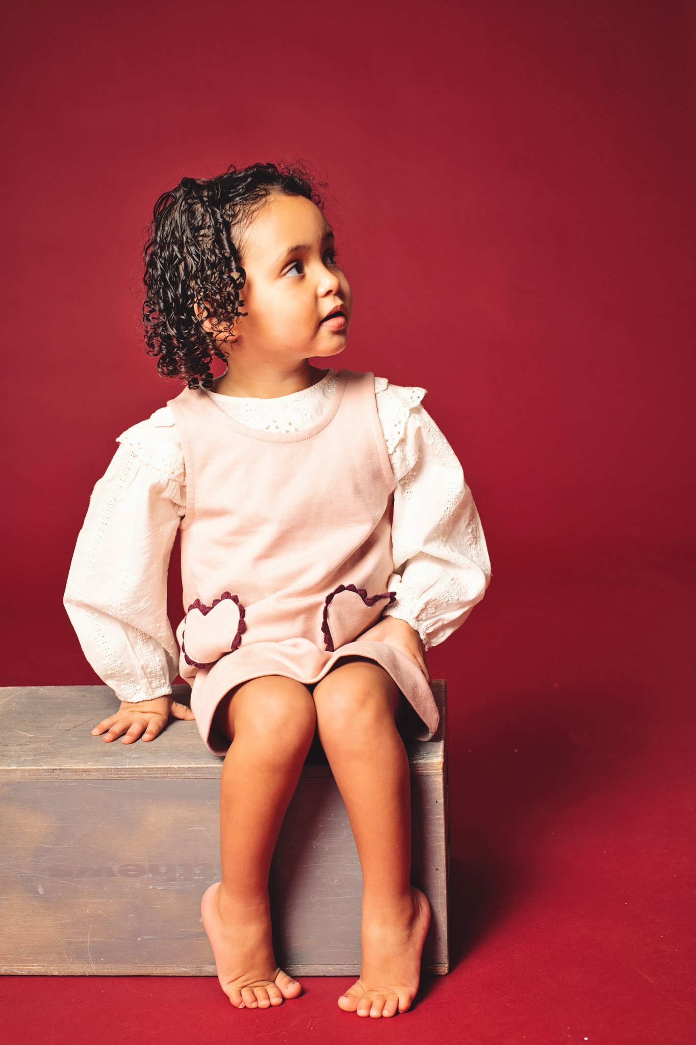 A girl sitting on an apple box on a wine backdrop