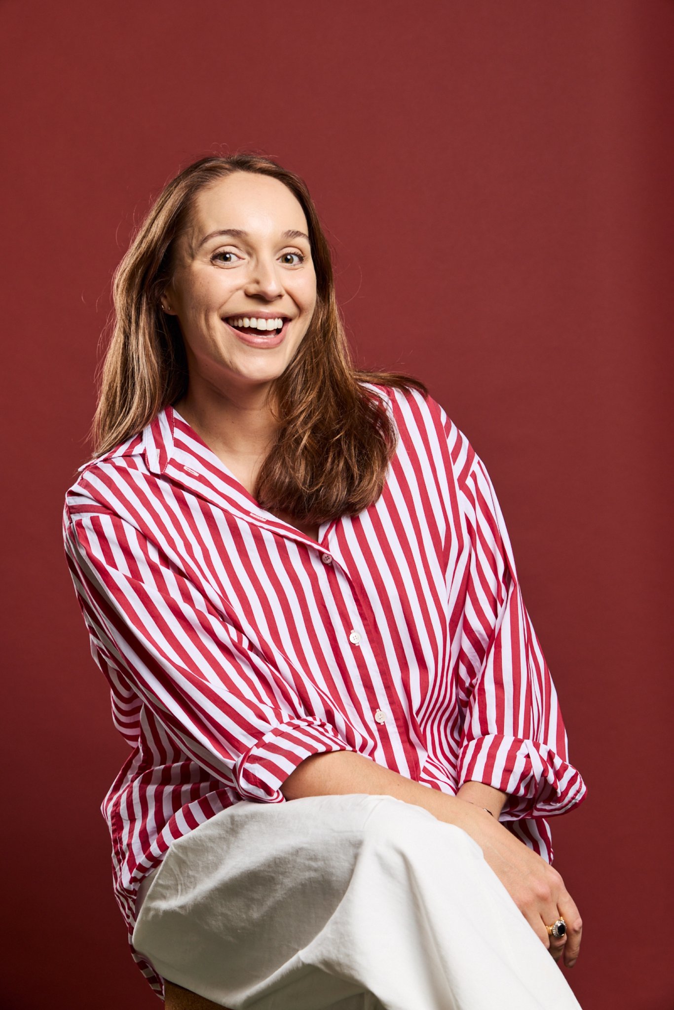 Briarley, Daysee co-founder, smiling in a red striped shirt on a deep red backdrop