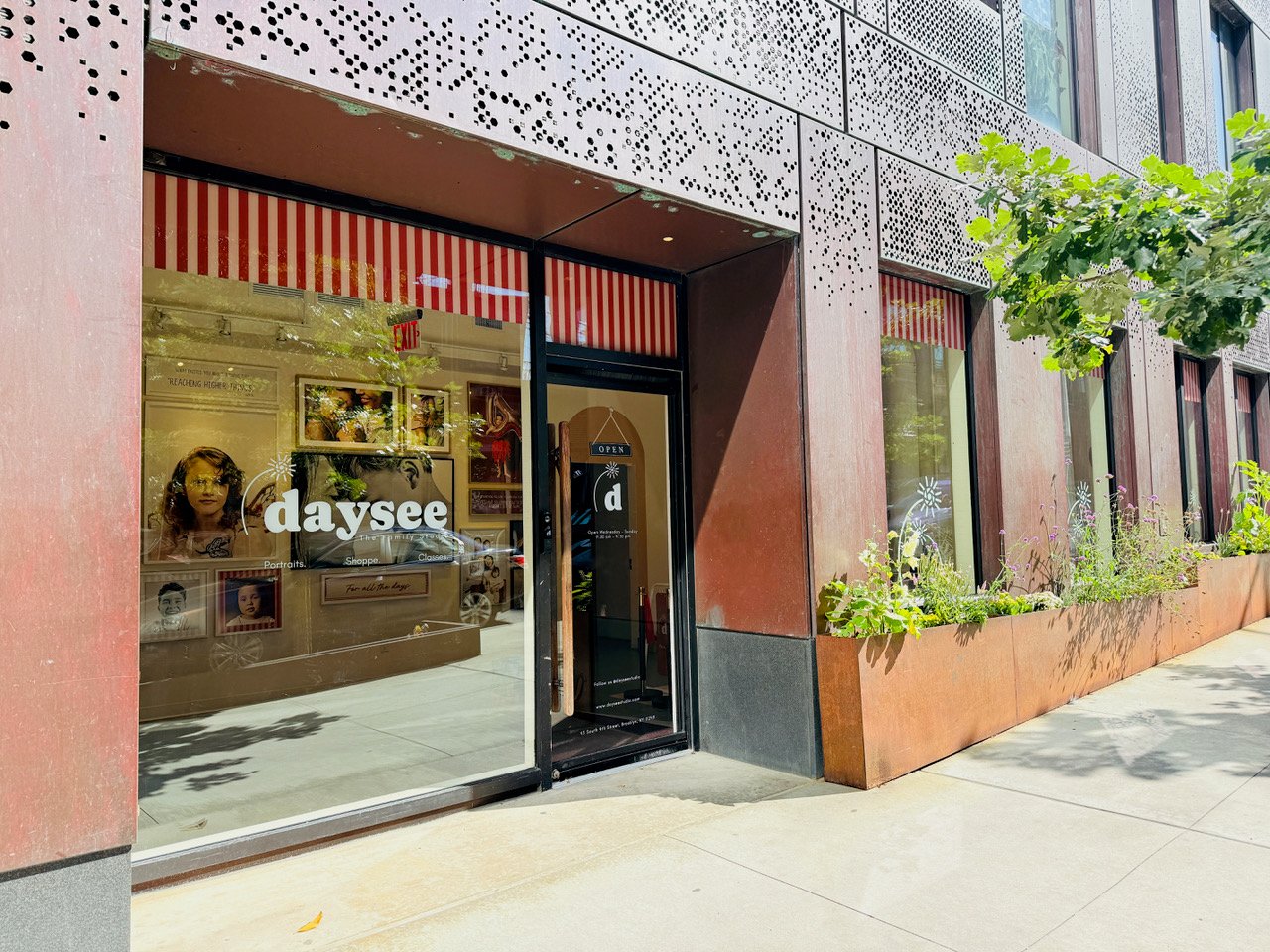 The daysee studio storefront on South 4th Street, with portraits and the logo in the window and the front door propped open