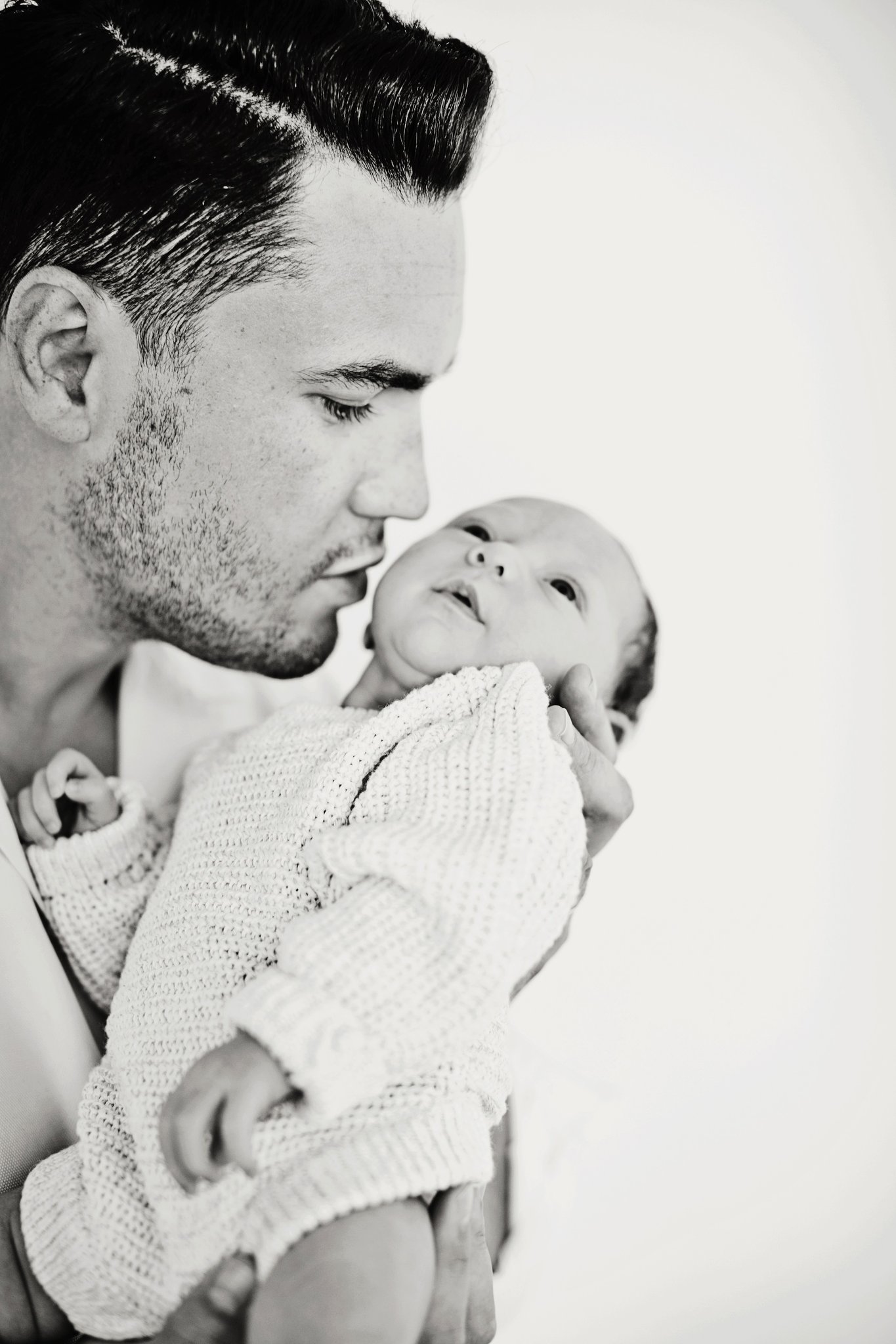 A father holding his newborn, in black and white