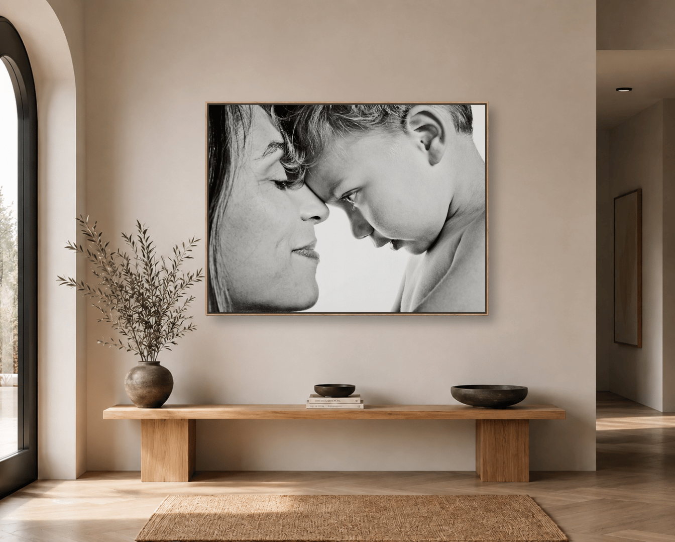 A black and white mother and child portrait framed in oak above a console table