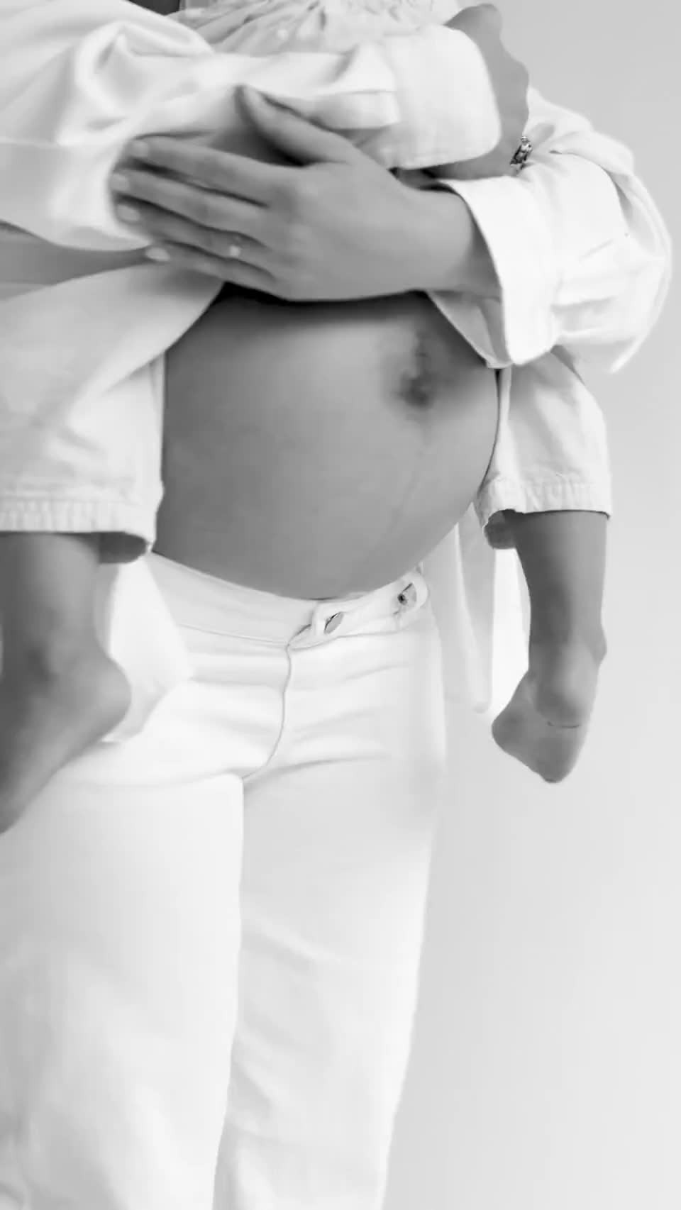 An expecting mother holding her toddler on her hip in the daysee studio