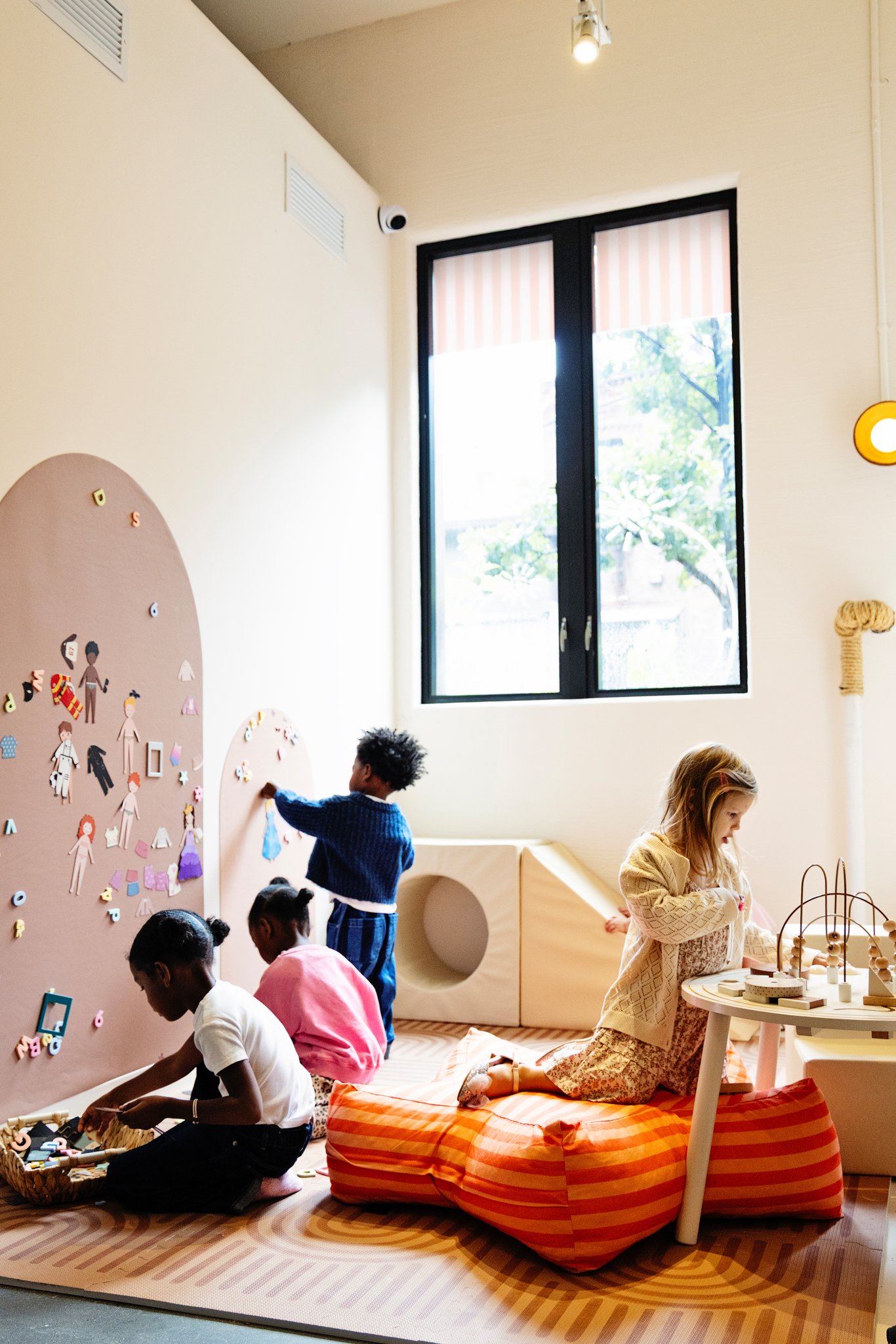 Kids playing by the magnet wall in the sunny playroom