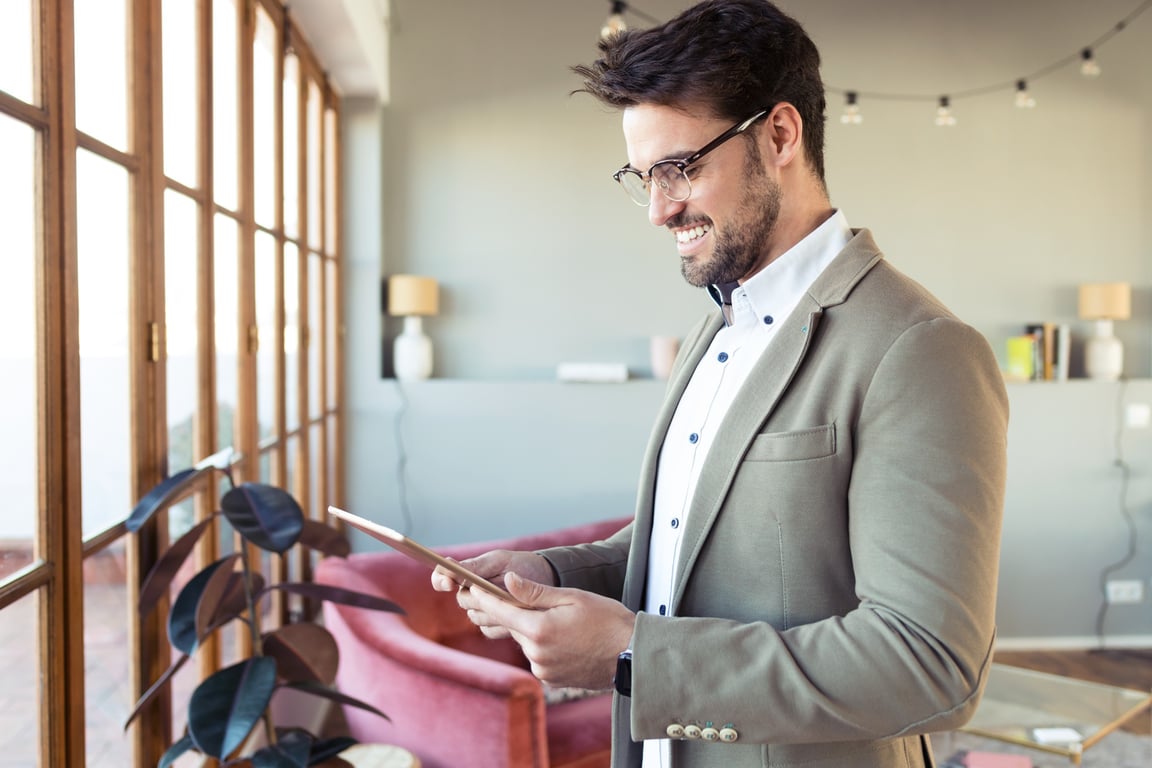 Smiling businessman using tablet to explore hotel upselling options