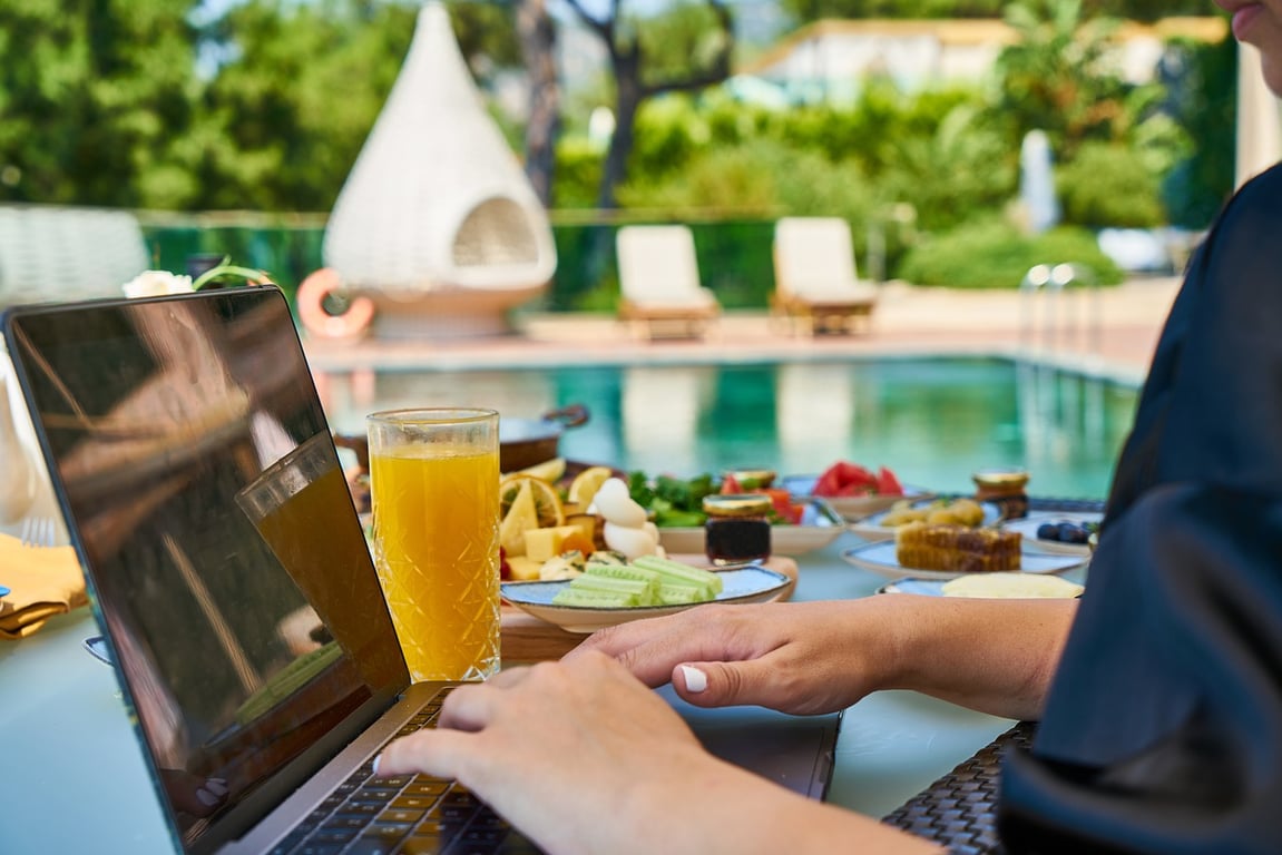Man working on his laptop next to hotel pool