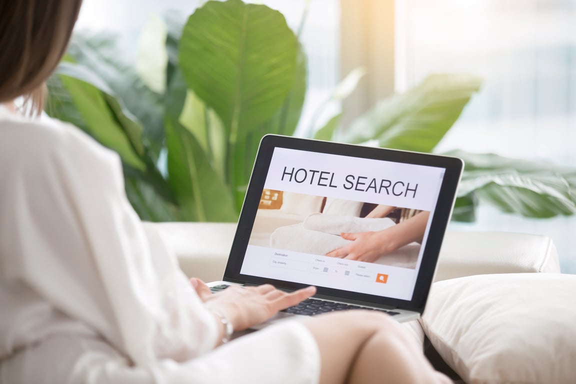Person using a laptop with a hotel search interface on the screen