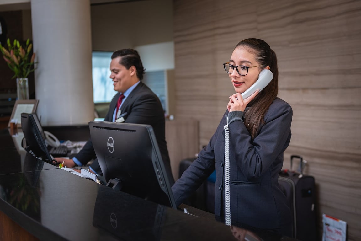 Two hotel managers working the reception handling guest queries.