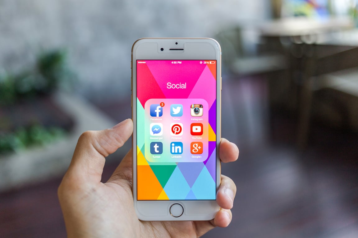 Person holding smartphone with colorful social media app icons displayed