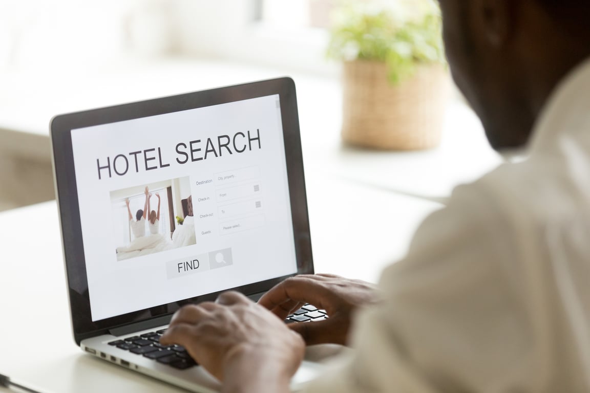 Person typing "hotel search" on a laptop, searching for accommodations online