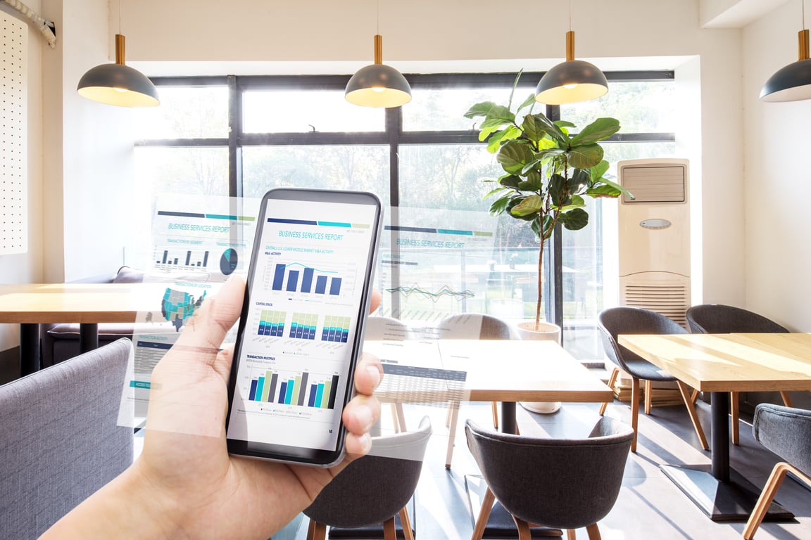 A mobile device displaying a revenue management system dashboard with data visualization, highlighting cloud technology integration in a modern office setting.