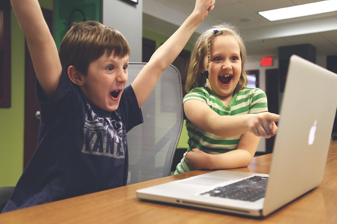 Two kids excited while looking at the computer.