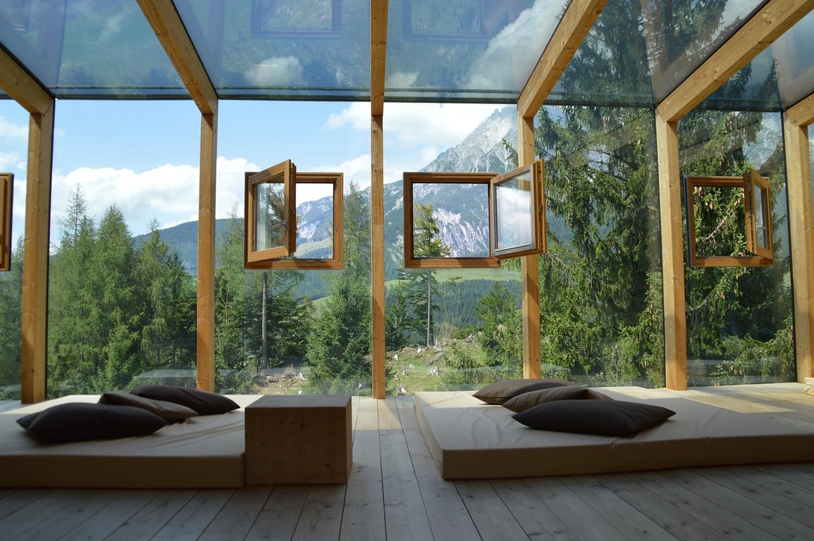 Floor mattresses and framed nature views convey a tranquil, grounded environment, helping users and search engines understand its minimal, nature-focused appeal.