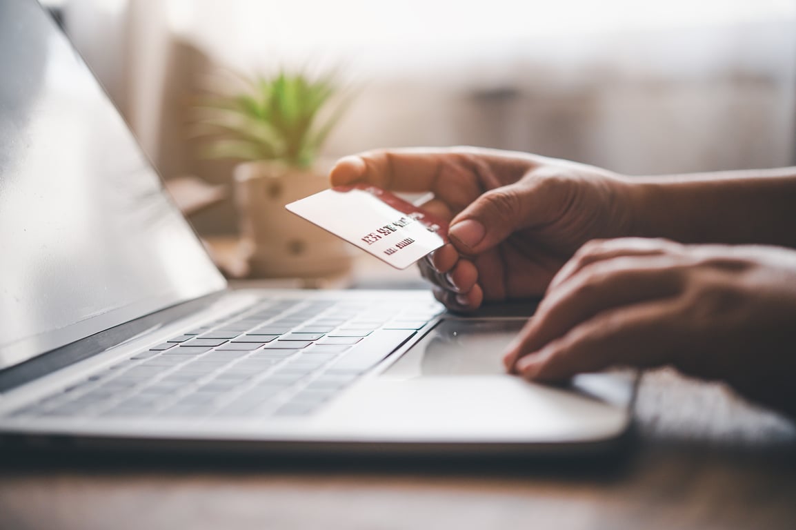 Close-up of a person holding a credit card while using a laptop to complete a secure online hotel booking, demonstrating a frictionless payment process.