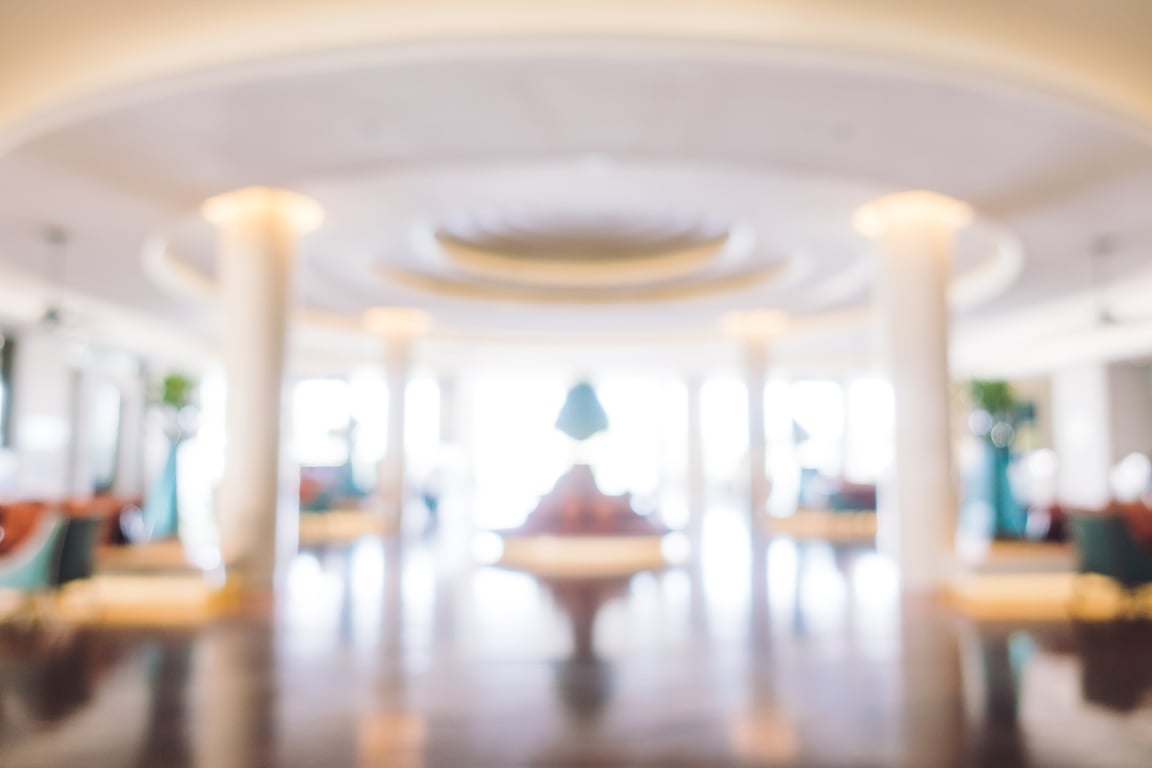 Blurred hotel lobby interior with elegant columns and seating areas representing hospitality management systems