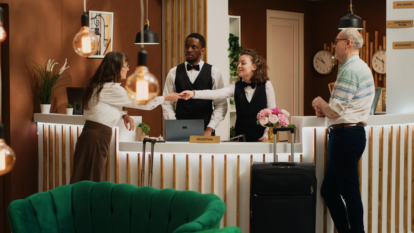 A hotel manager reviewing an automation dashboard on a tablet with staff, displaying hotel operations automation data.