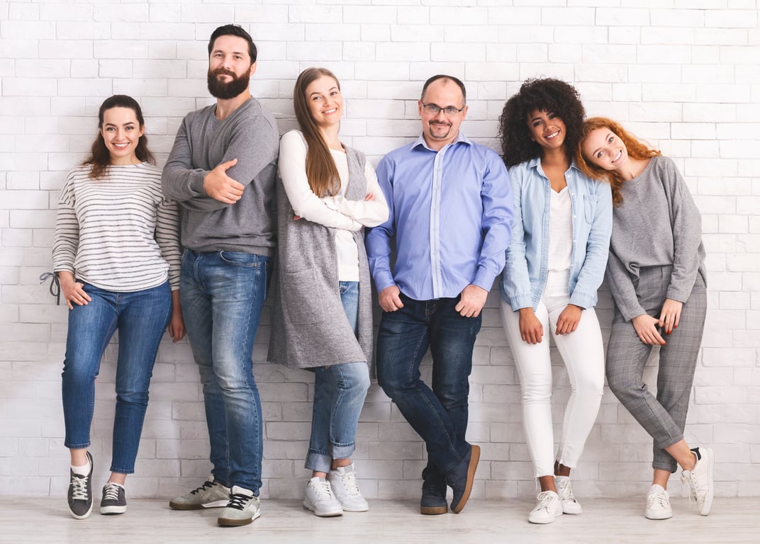 Diverse hotel team standing against a white brick wall