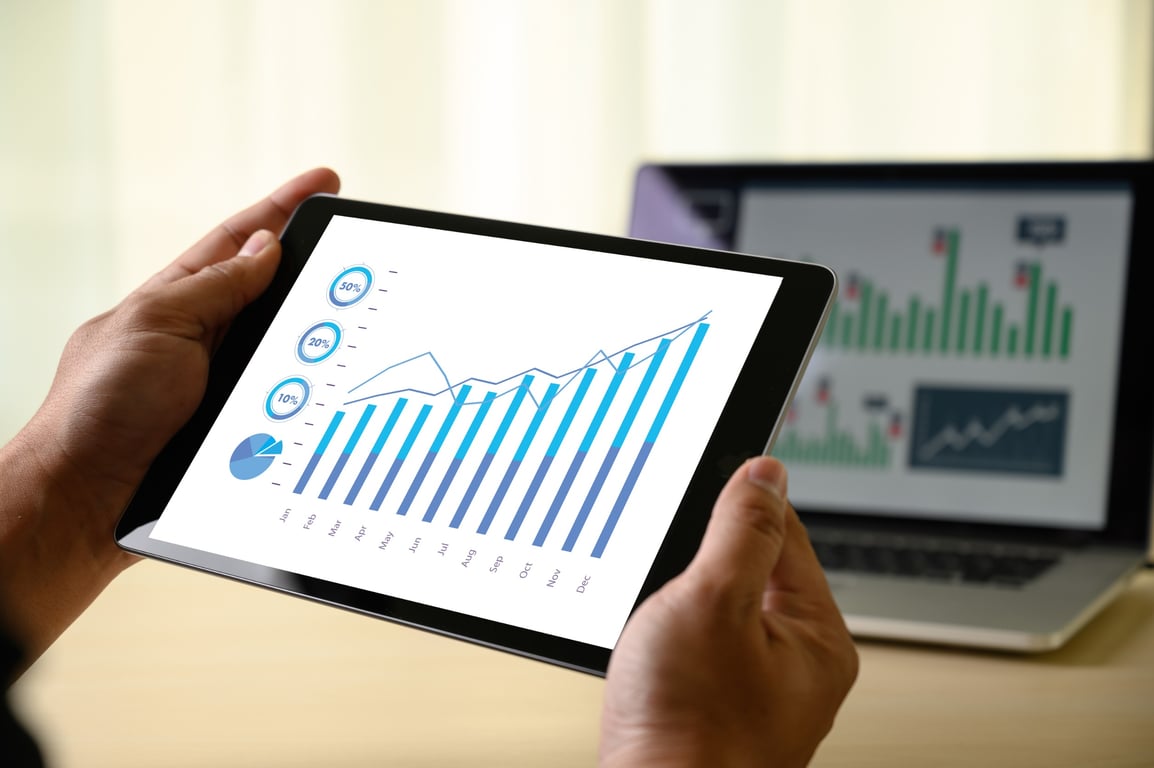 Executive holding a tablet displaying financial charts related to hotel accounting software insights.