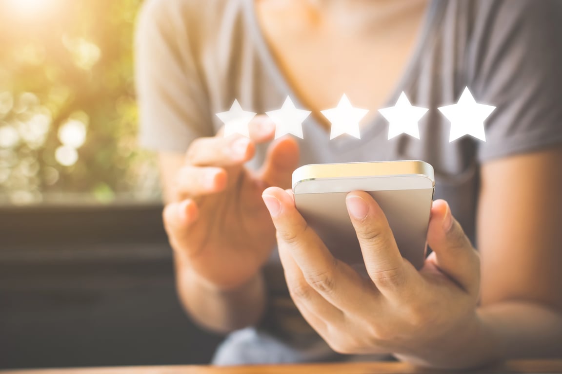 Woman leaving a 5-star review on her mobile device to enhance the hotel