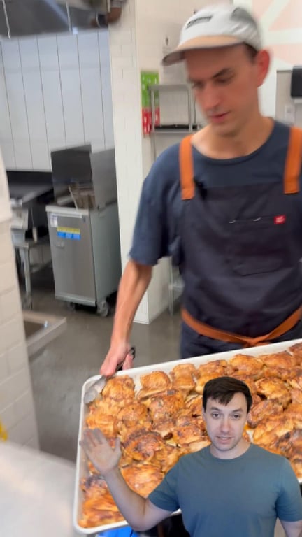 A Full Time Food chef carrying a full sheet tray of roasted chicken in an Austin commissary kitchen